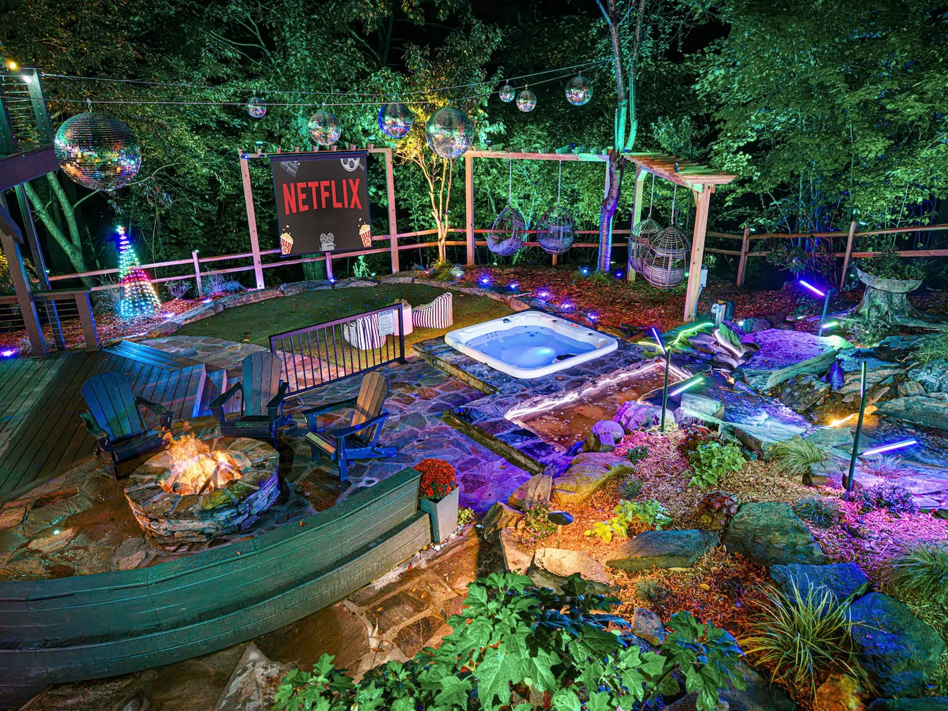 Outdoor Netflix-themed backyard with hot tub, fire pit, swings, and disco balls.