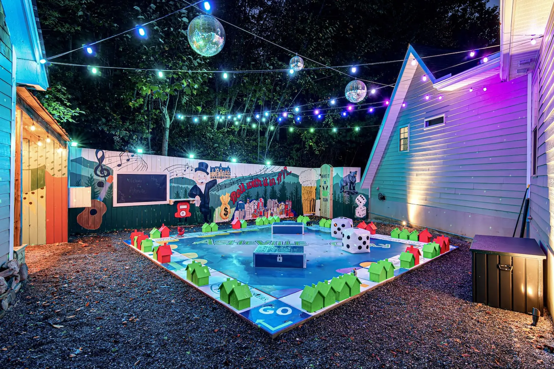 Giant Monopoly board in a backyard with disco balls and string lights.