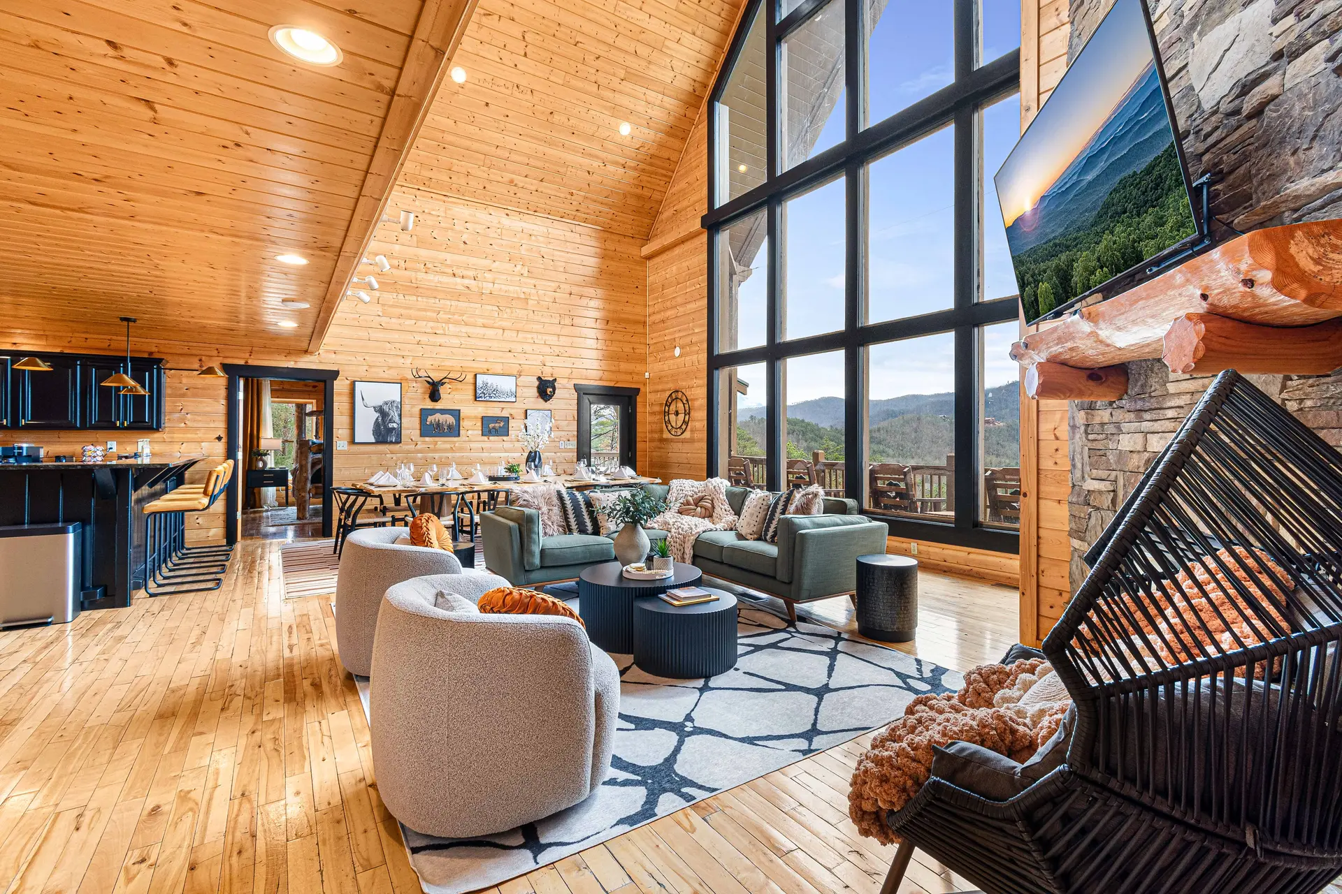 A living room with a stone fireplace, large windows, and a mountain view.