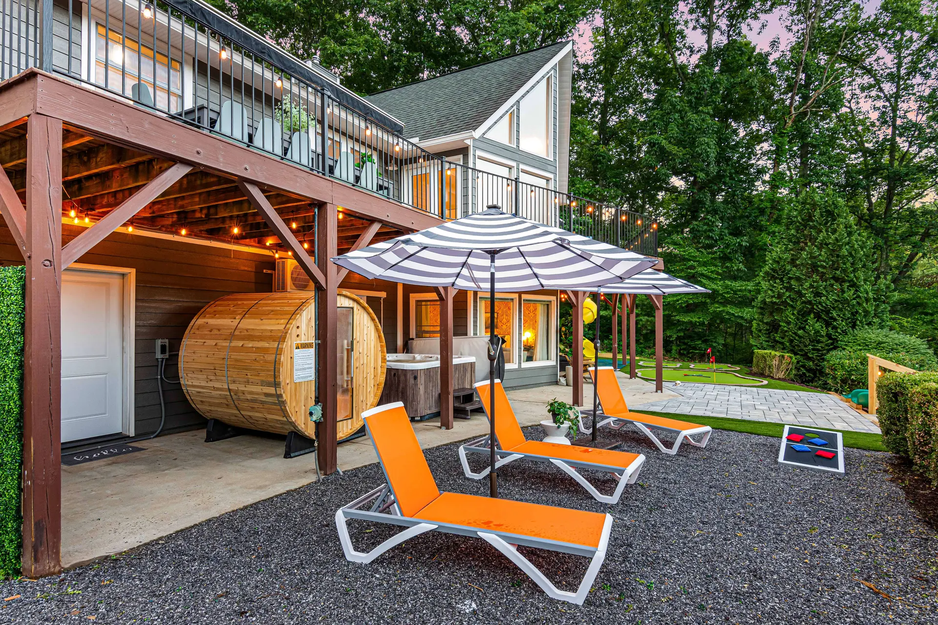 Backyard with hot tub, sauna, lounge chairs, and cornhole.