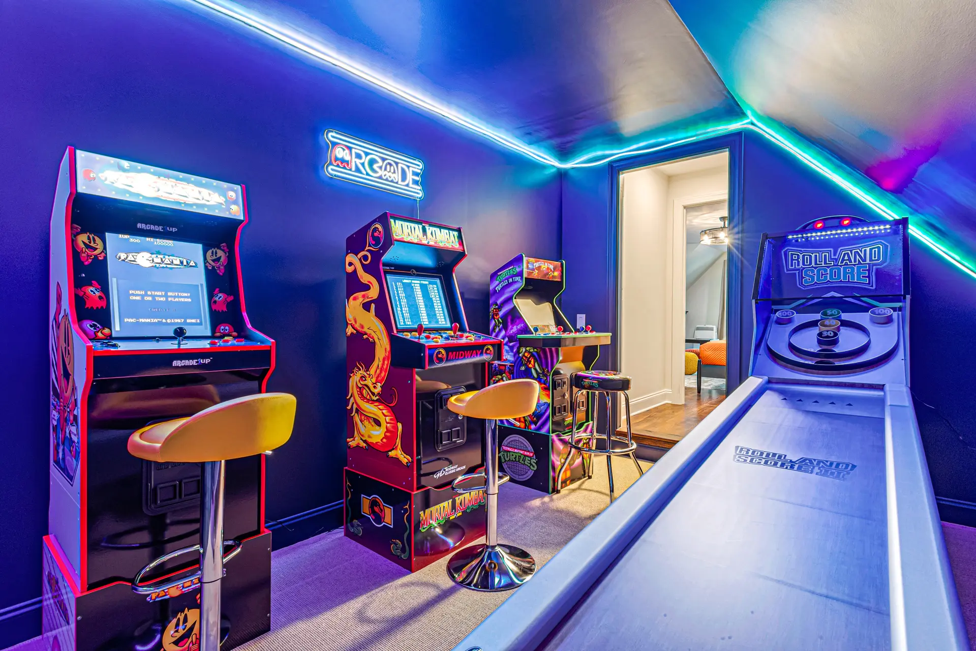 An arcade game room is brightly lit with neon blue and purple lights.