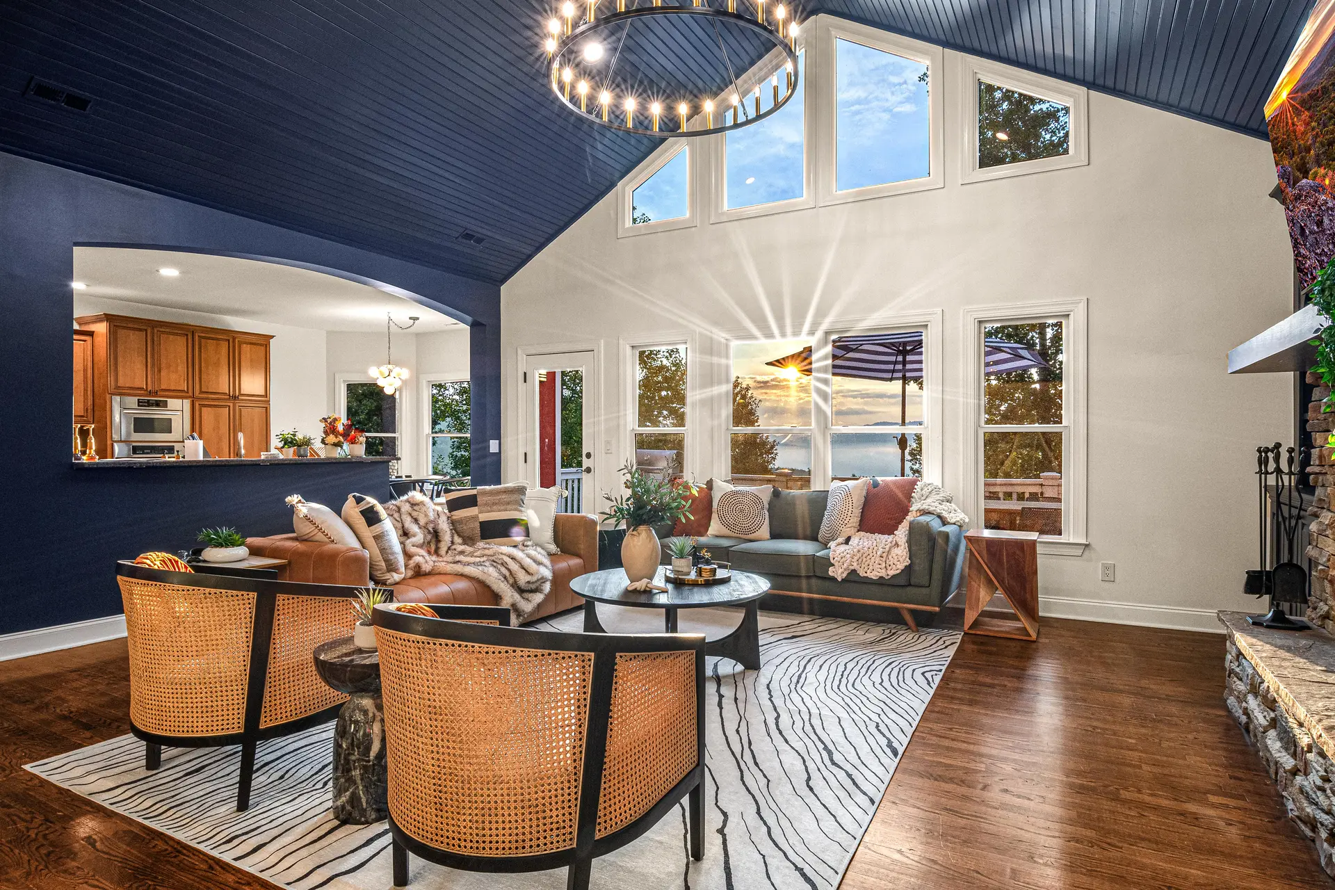 A beautifully decorated living room with a fireplace, large windows, and a view of the sunset.