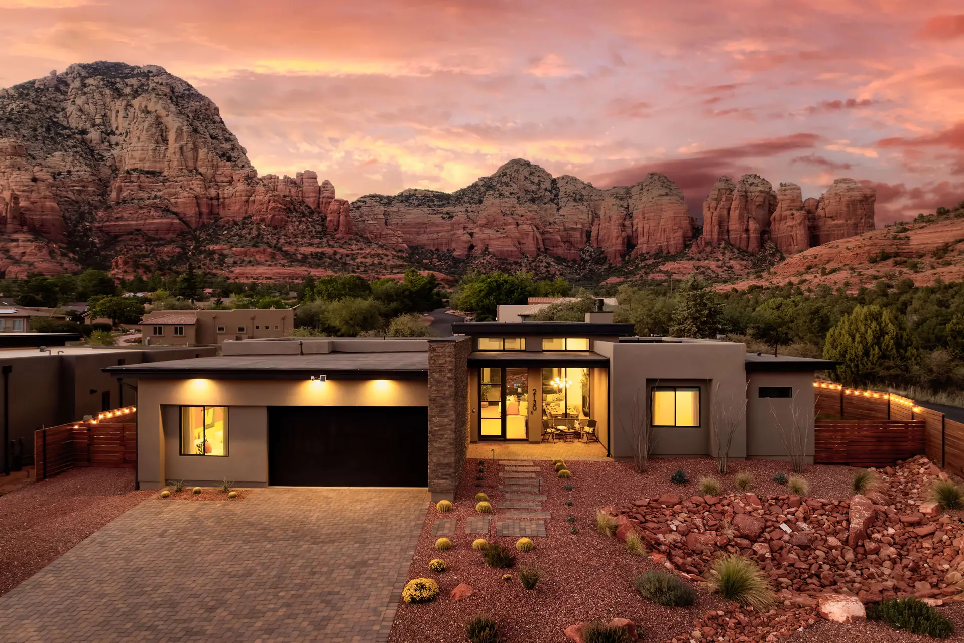 A modern home in Sedona, Arizona, with red rock mountains and a sunset sky.