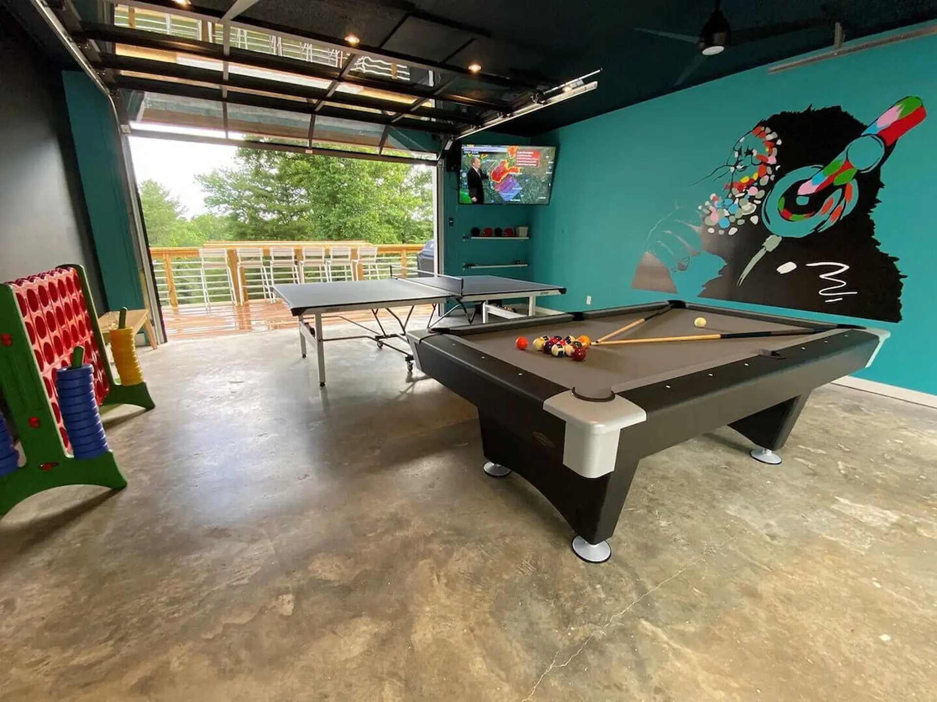 Pool table and ping pong table in a room with a mural of a monkey wearing headphones.