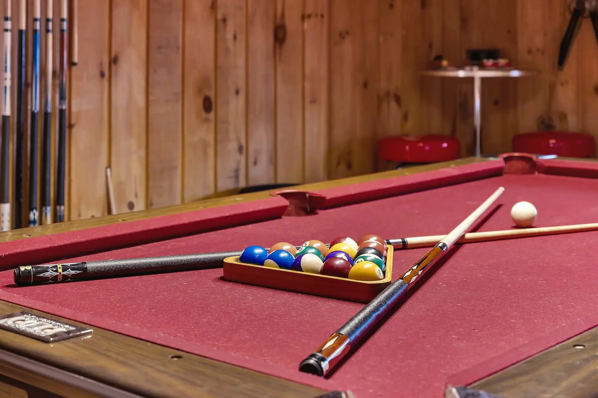 A pool table with billiard balls in a triangle rack, two cues, and a white cue ball.