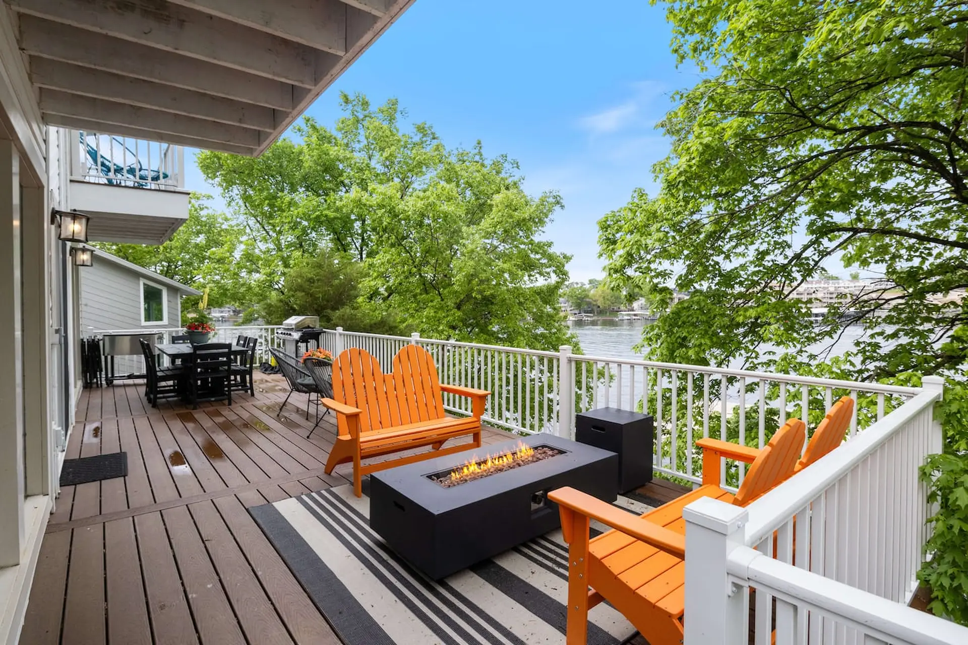 Deck overlooking water with fire pit, chairs, and dining table.