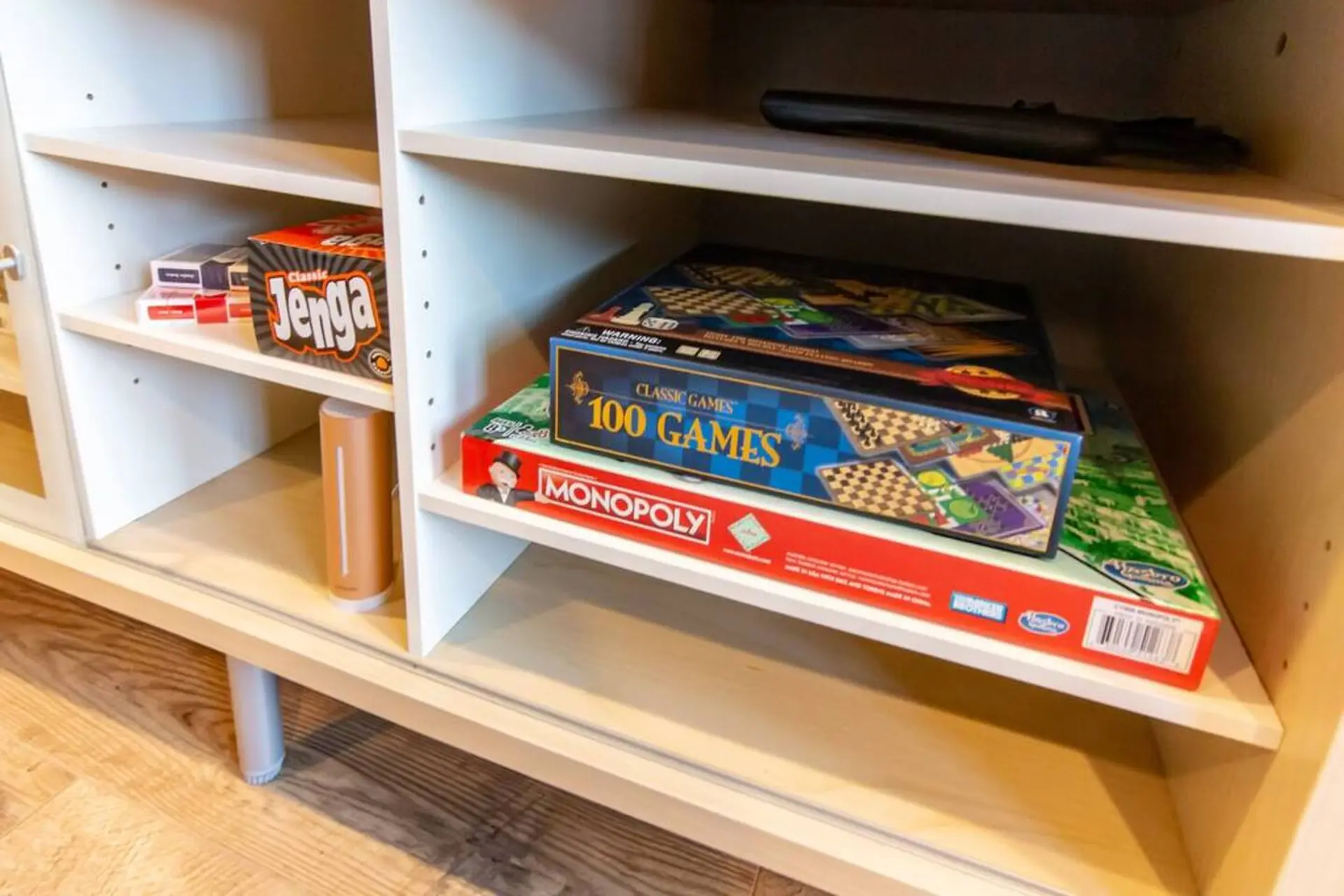 A cabinet filled with board games, including Jenga, Monopoly, and a 100 Games collection.
