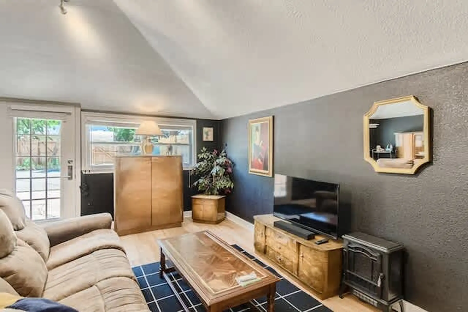 A living room with a couch, TV, coffee table, fireplace, and a mirror.
