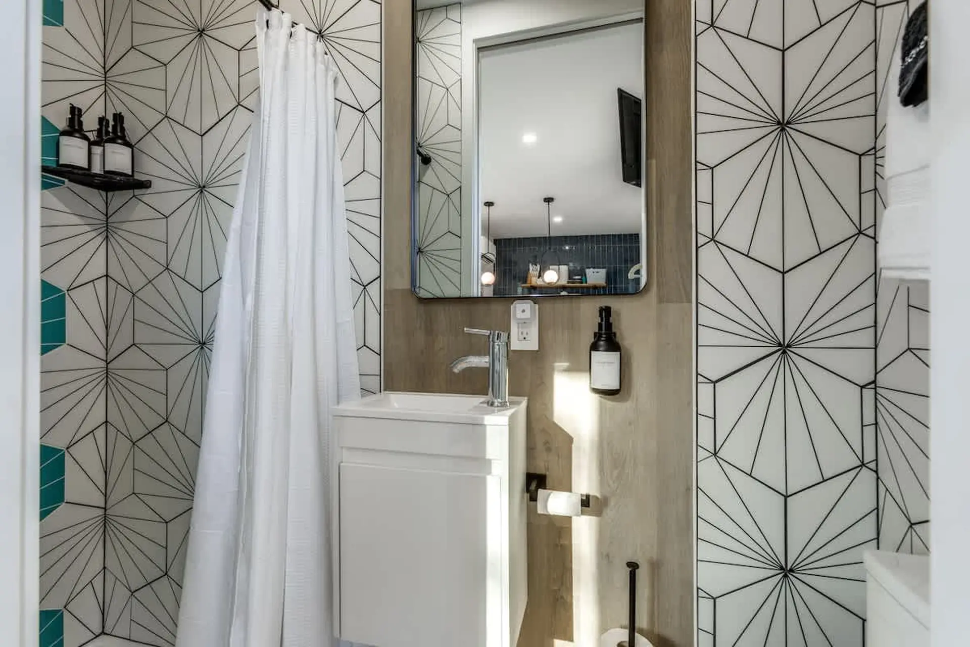 Modern bathroom with geometric tiles, a white vanity, and a mirror.