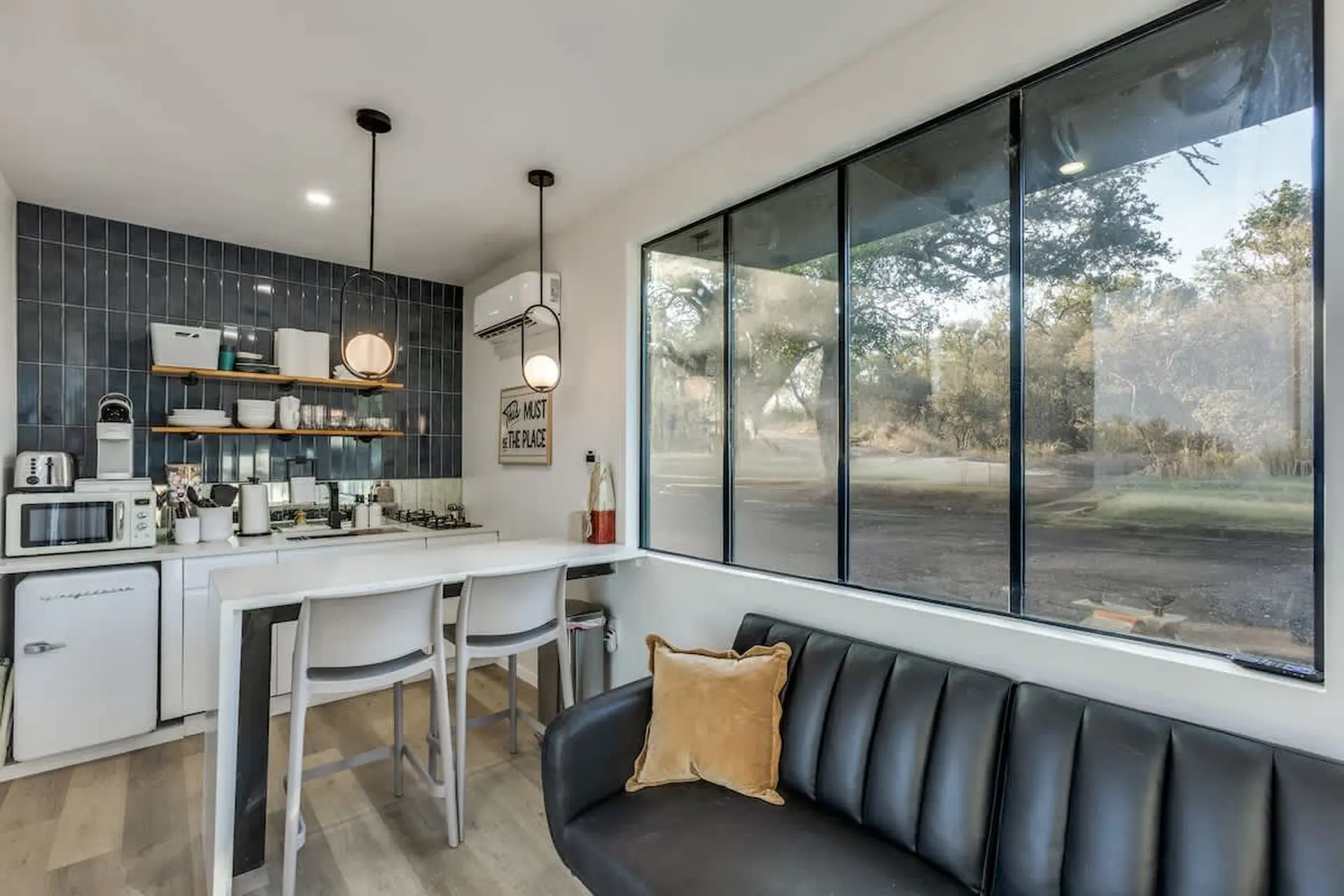 Modern kitchen with minimalist decor and large windows overlooking a natural landscape.