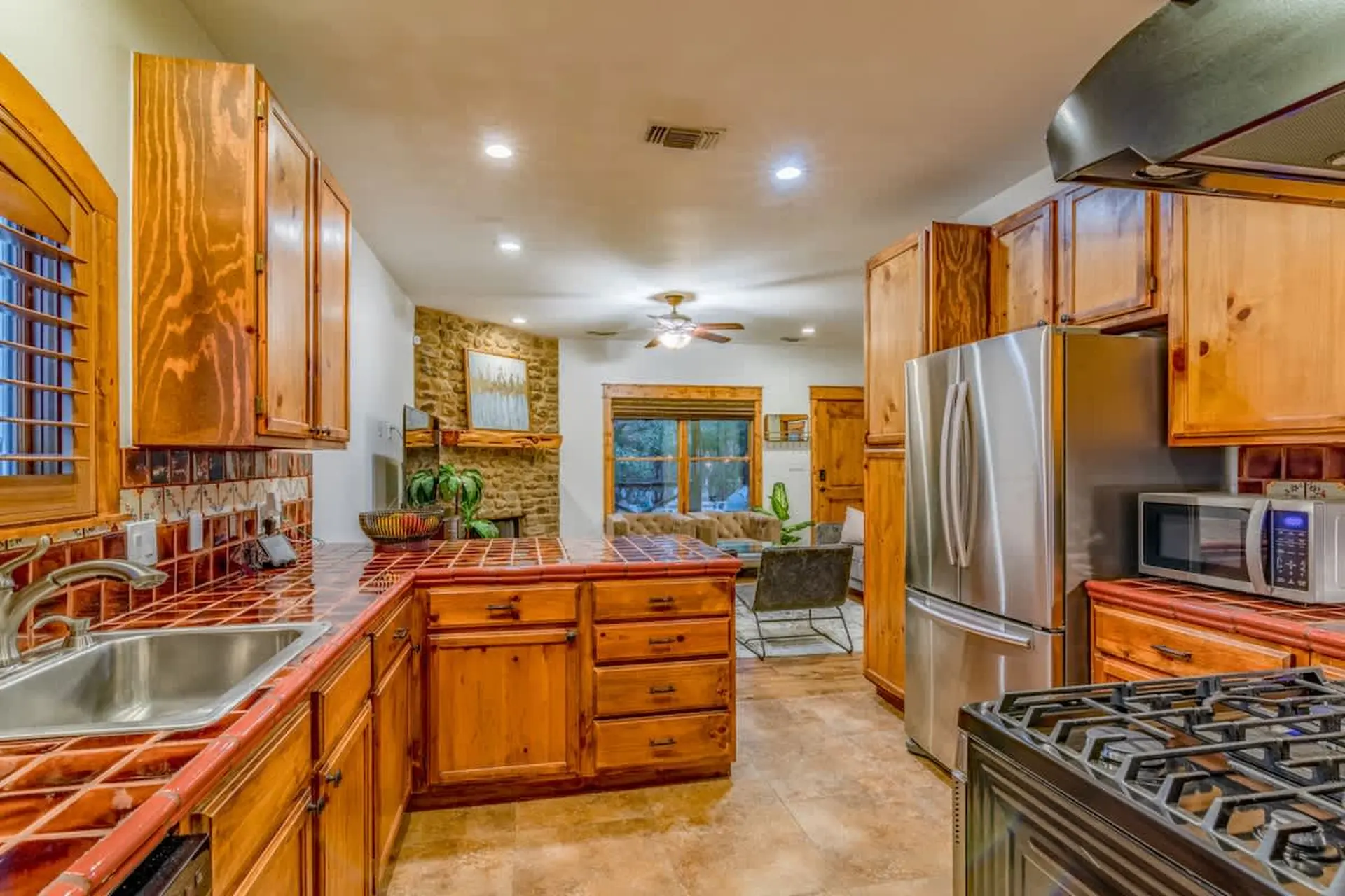 A kitchen with wooden cabinets, stainless steel appliances, and tile countertops.