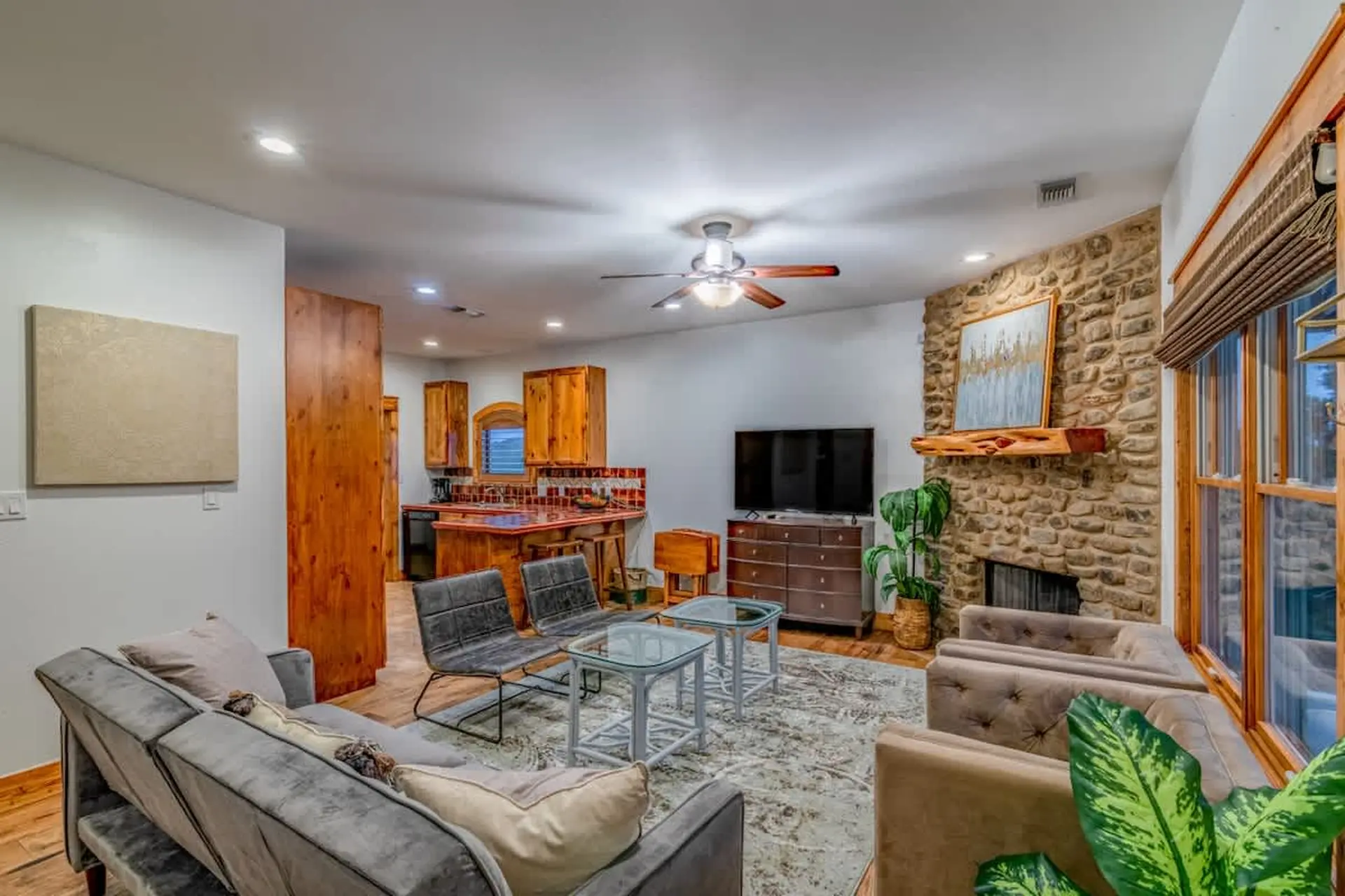 A living room with a grey sofa, stone fireplace, and kitchen island.