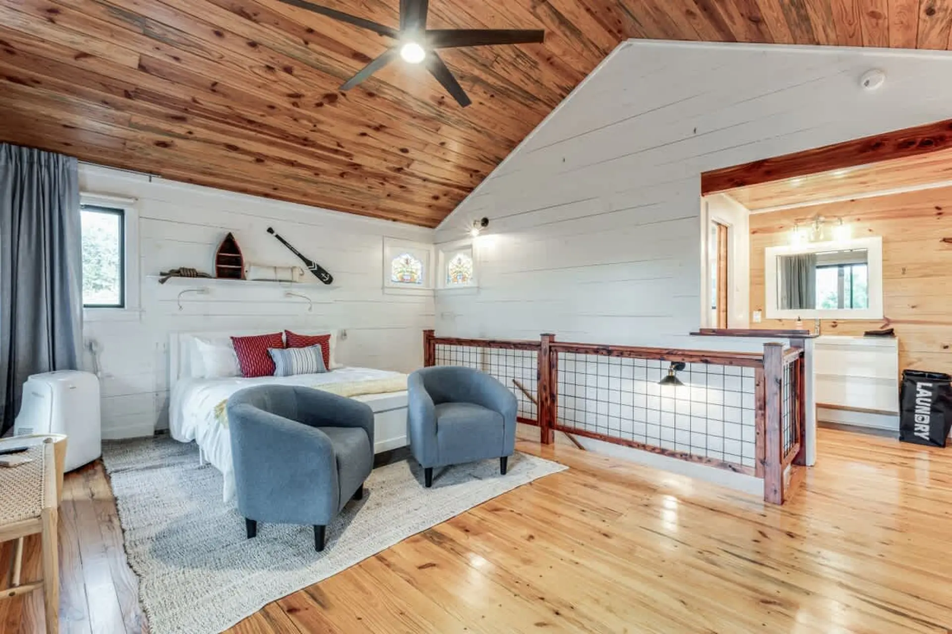 Loft bedroom with two chairs, bed, and bathroom.