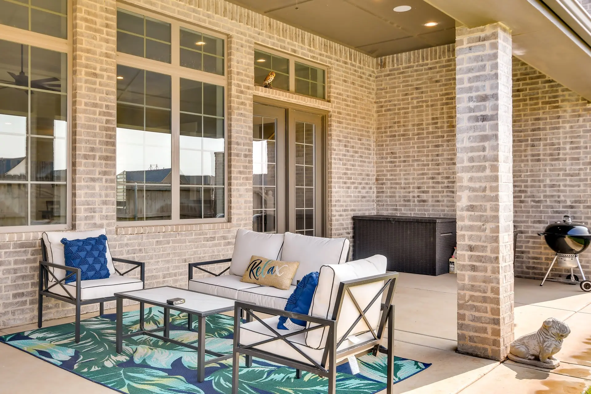 An outdoor patio with seating, a grill, and a dog statue.