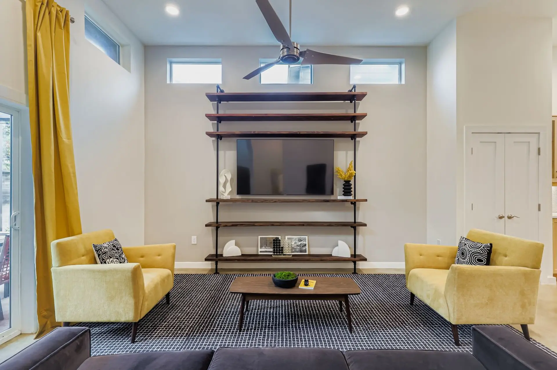 A living room with a sectional sofa, two yellow chairs, and a TV stand.