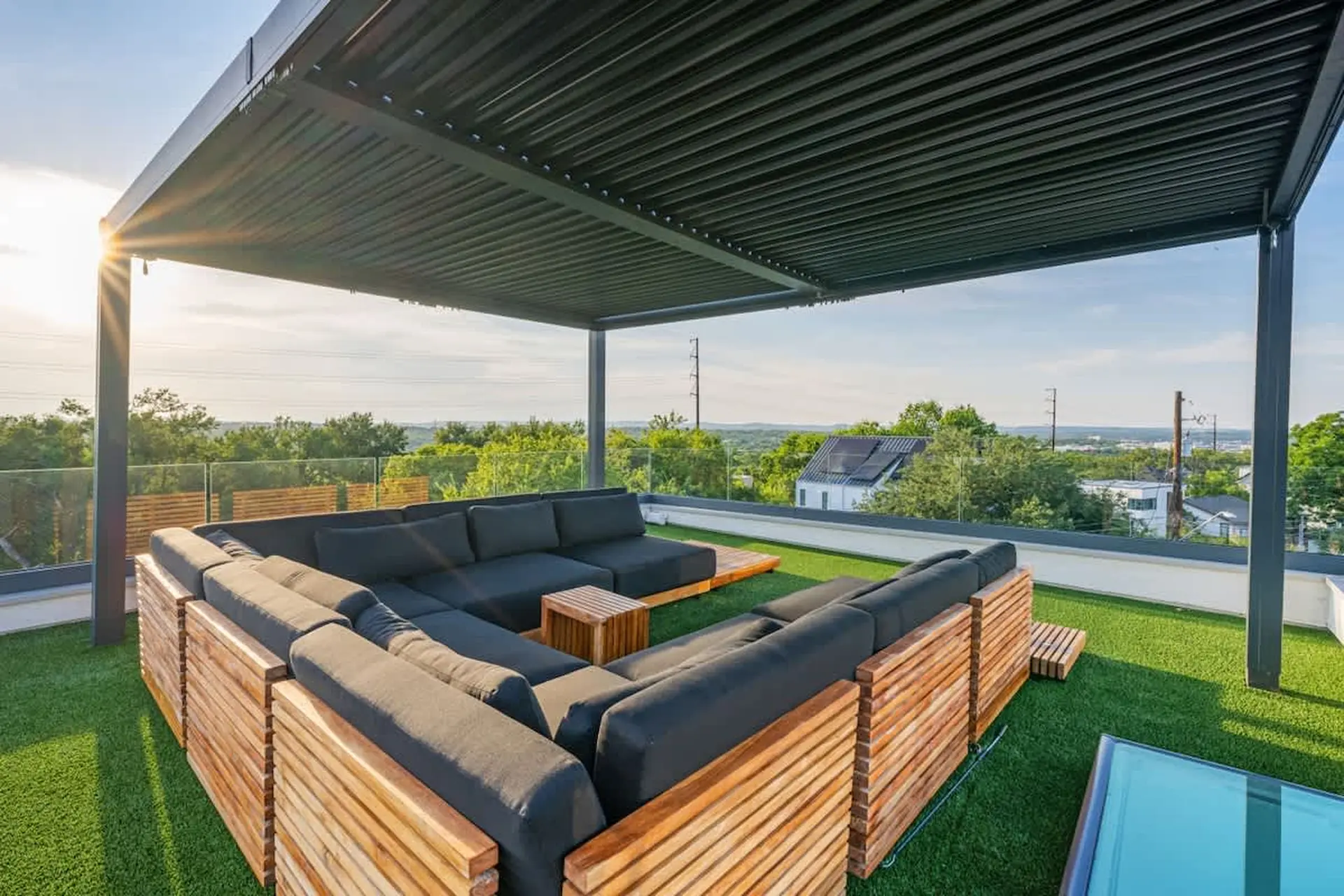 Rooftop patio with large sectional sofa, wooden accents, and city views.
