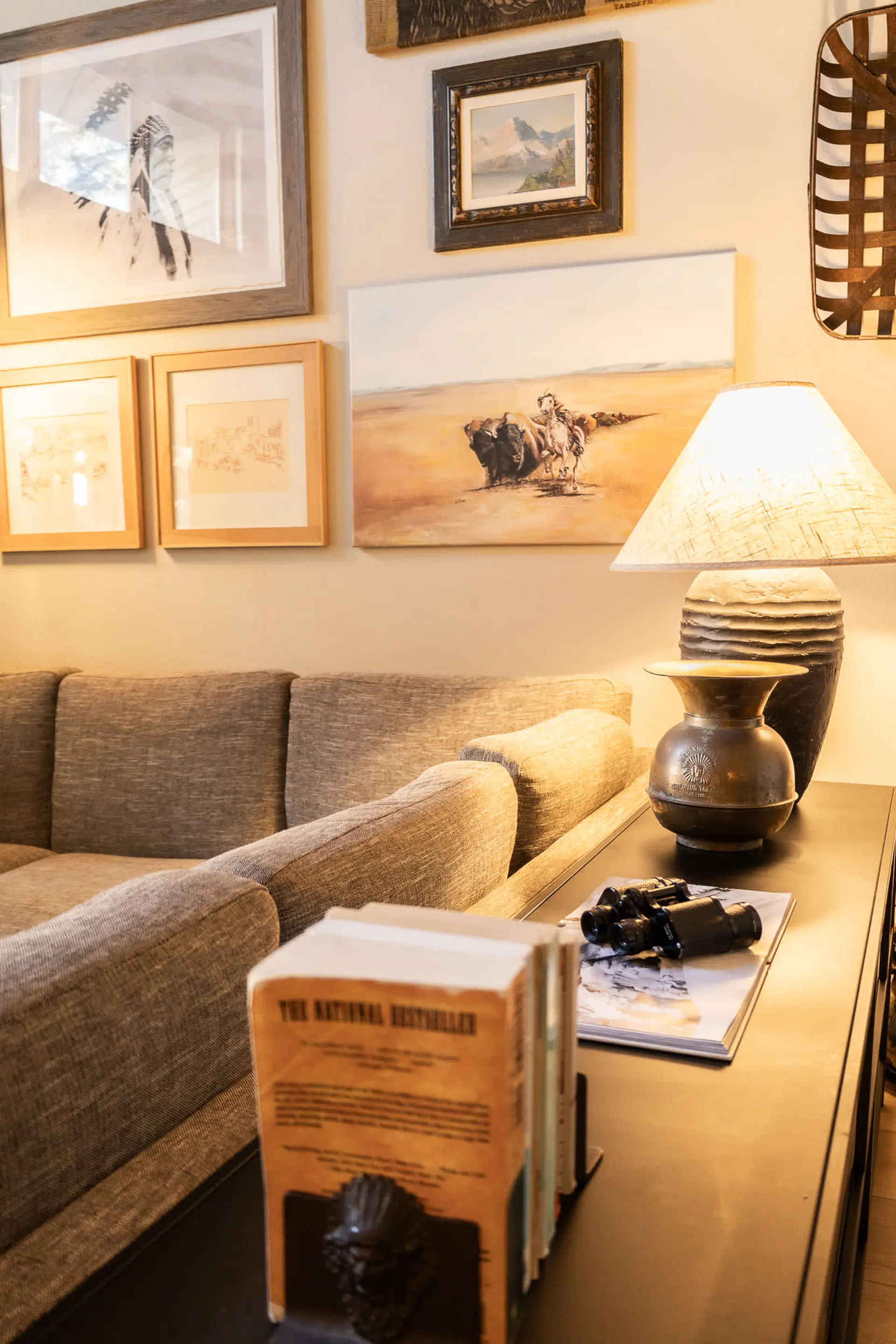 A cozy living room with a couch, lamp, and framed artwork.