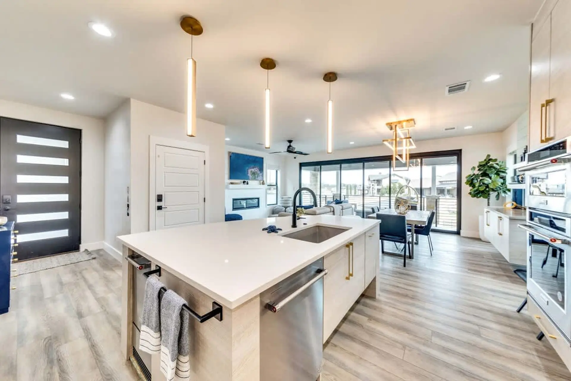 Modern open-concept kitchen and living area with island, fireplace, and large windows.