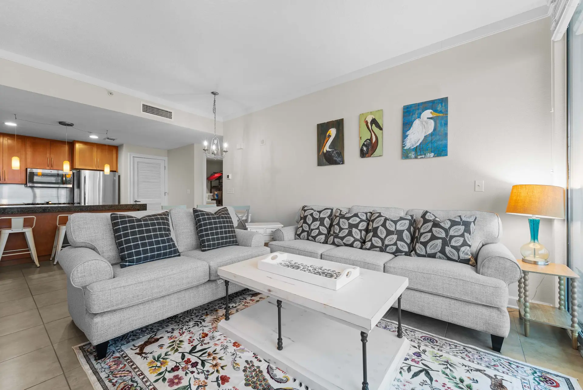 A living room with a gray sofa, coffee table, and artwork of pelicans on the wall.