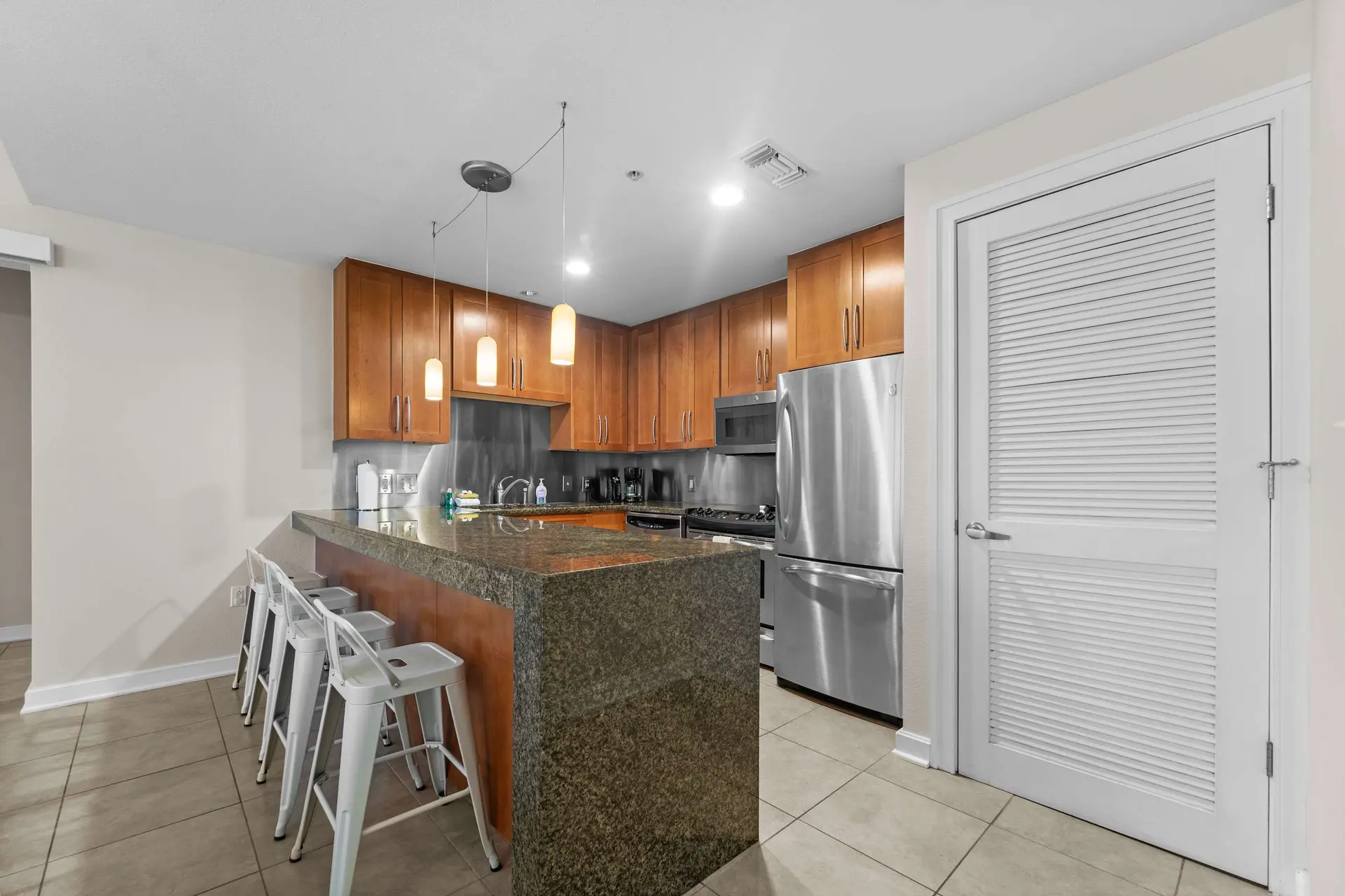 Kitchen with a granite island, stainless steel appliances, and wood cabinets.