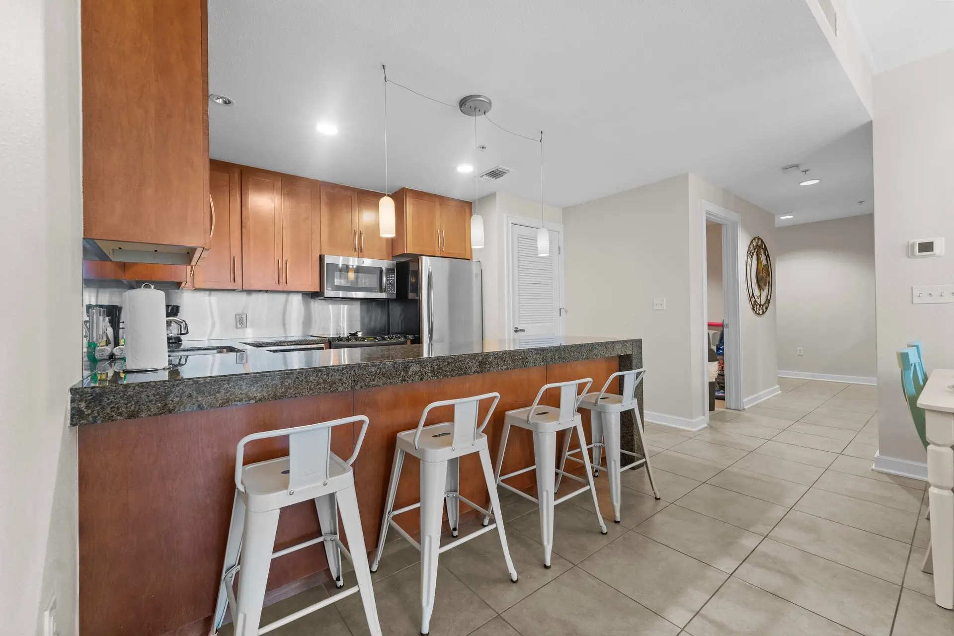 Kitchen with a granite countertop bar, wooden cabinets, stainless steel appliances, and white bar st