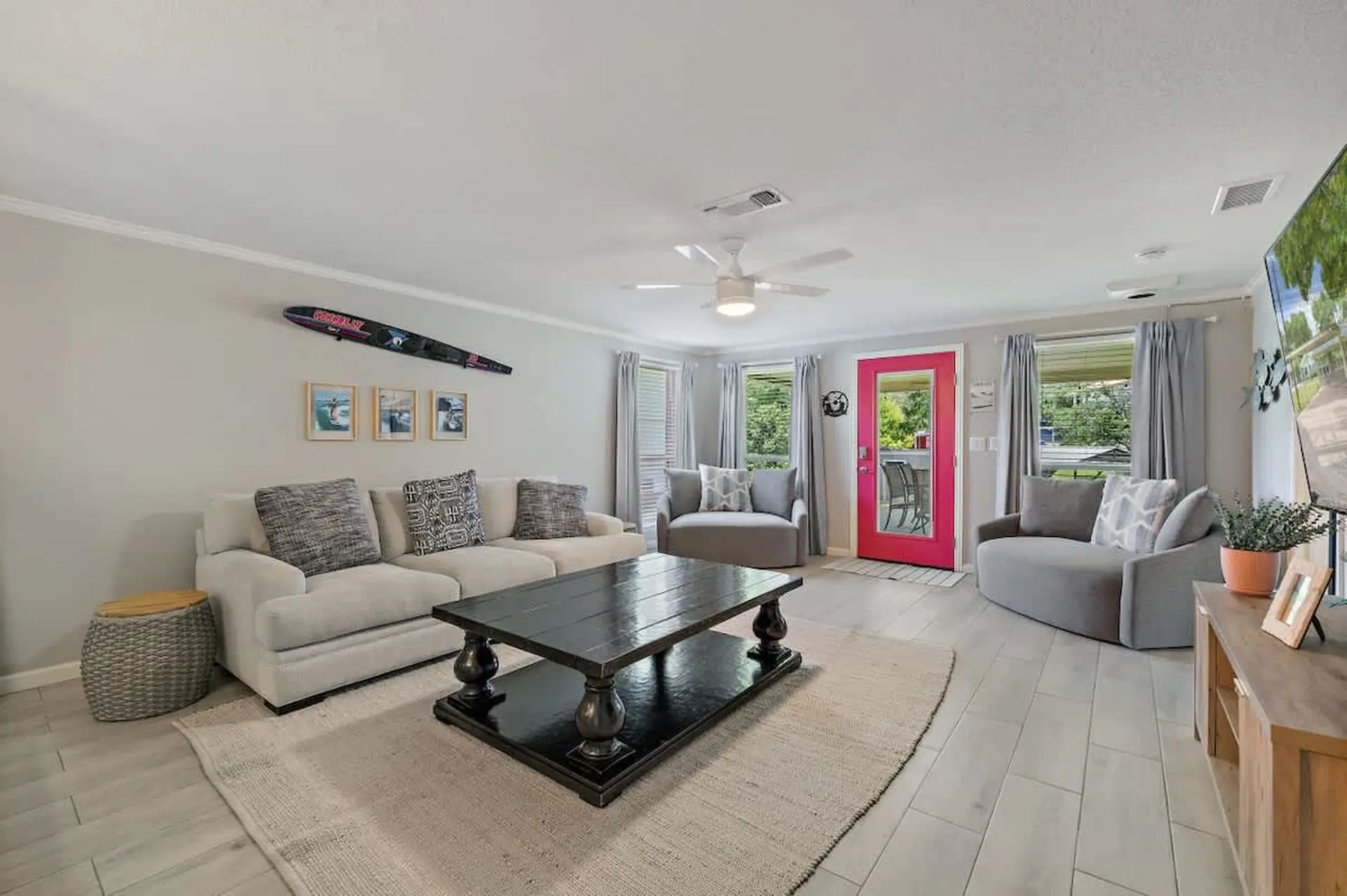 A living room with a sectional sofa, coffee table, and a pink door.