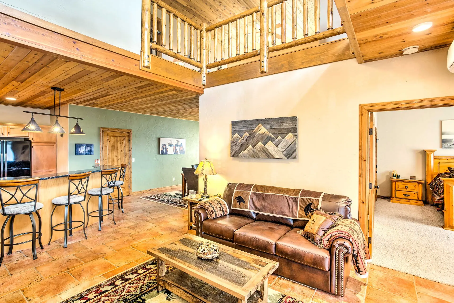 A rustic living room with a leather sofa, wooden accents, and mountain-themed decor.