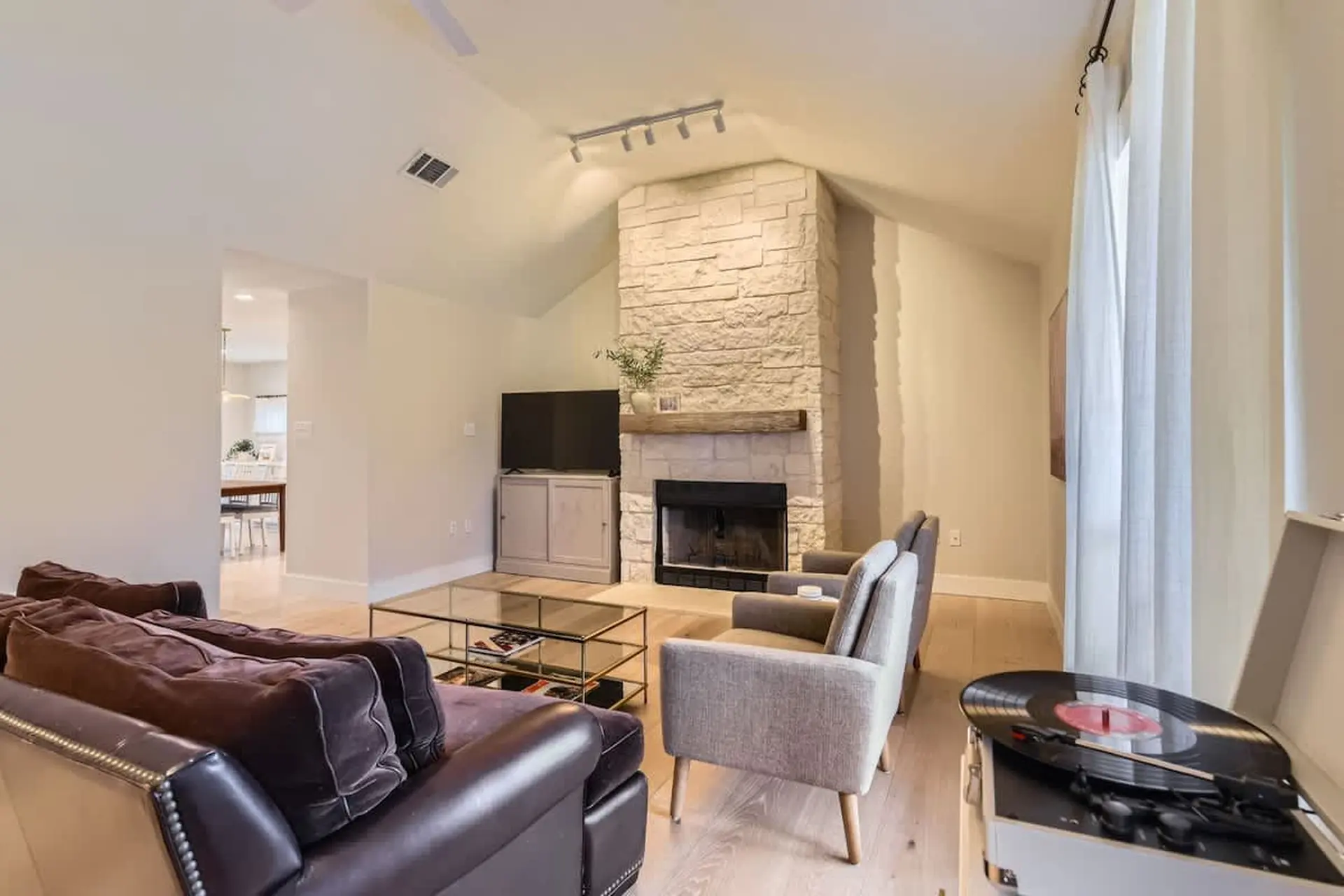 A living room with a stone fireplace, a dark couch, and a record player.