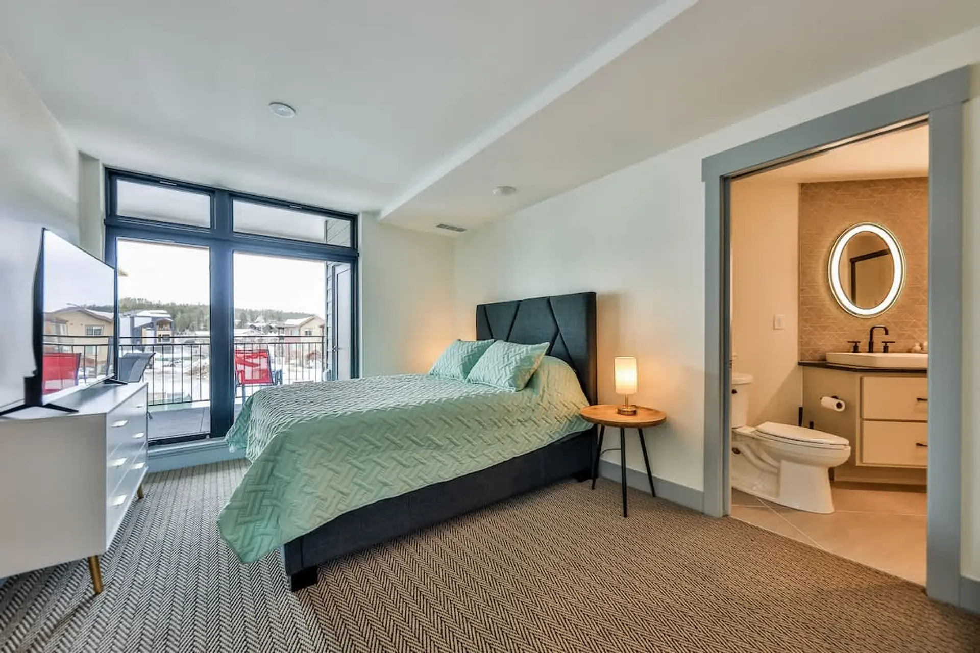 A bedroom with a king-sized bed, dresser, and a doorway to a bathroom.