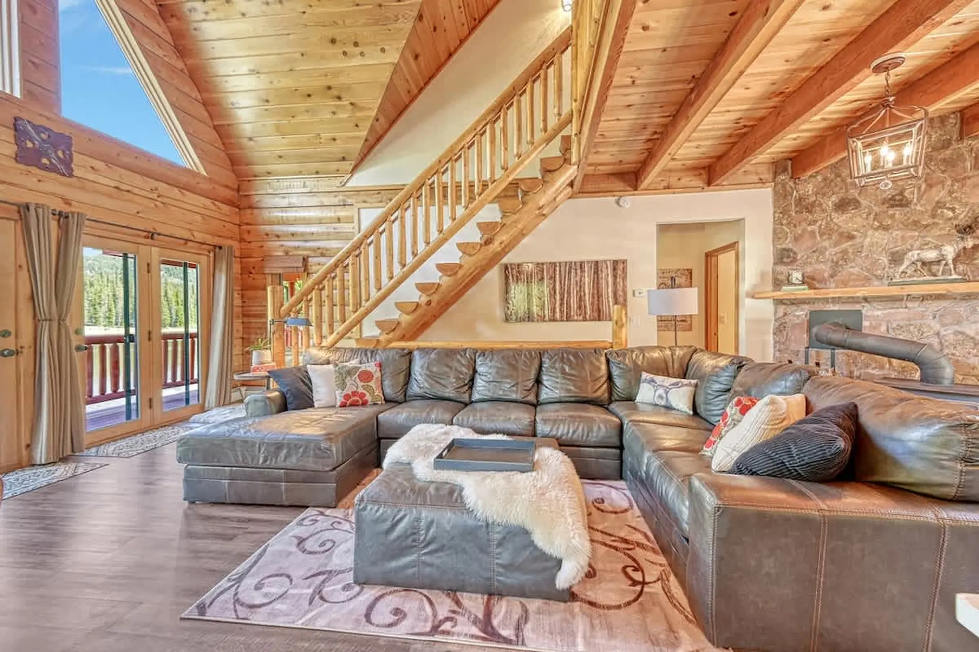 Living room with a large leather sectional sofa and fireplace in a log cabin.