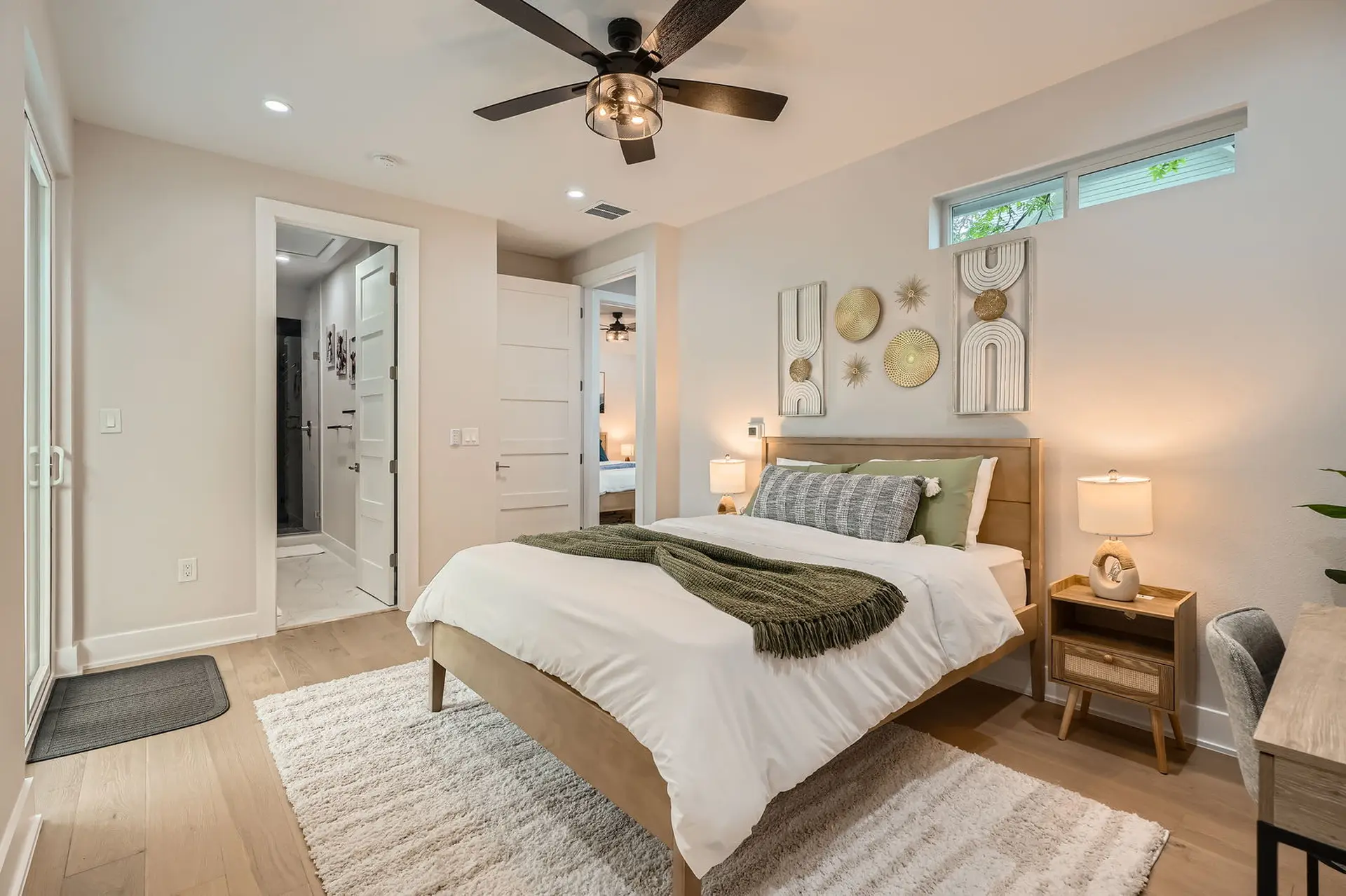 A bedroom with a wooden bed, green blanket, and modern decor.