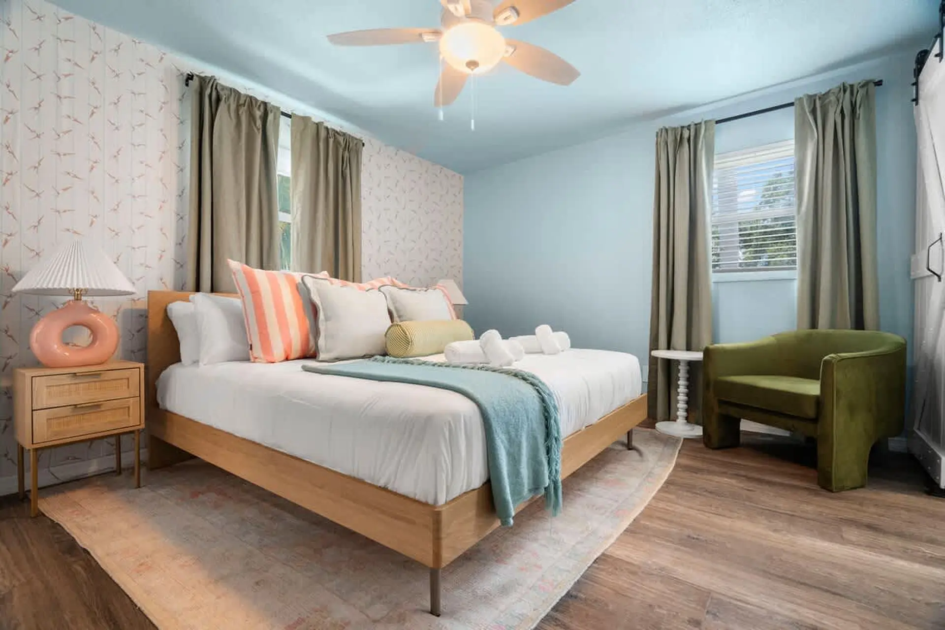 A bedroom with a bed, armchair, and ceiling fan.