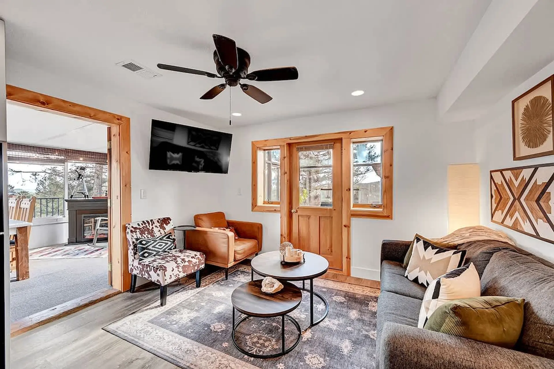 Living room with a sofa, armchair, cow-print chair, coffee tables, and a TV.
