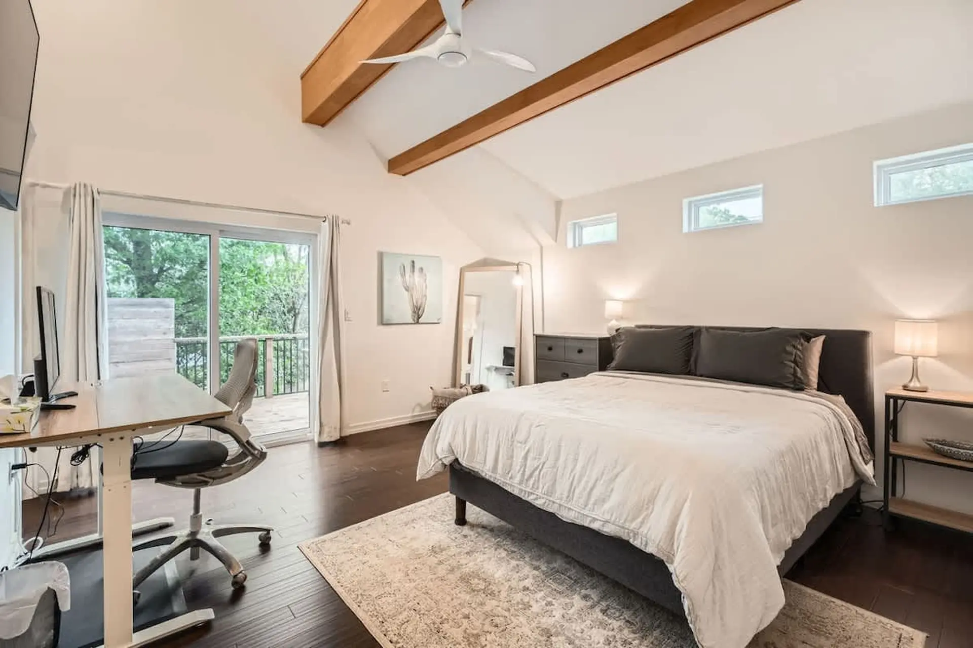 Bedroom with a bed, desk, and sliding glass door leading to a deck.