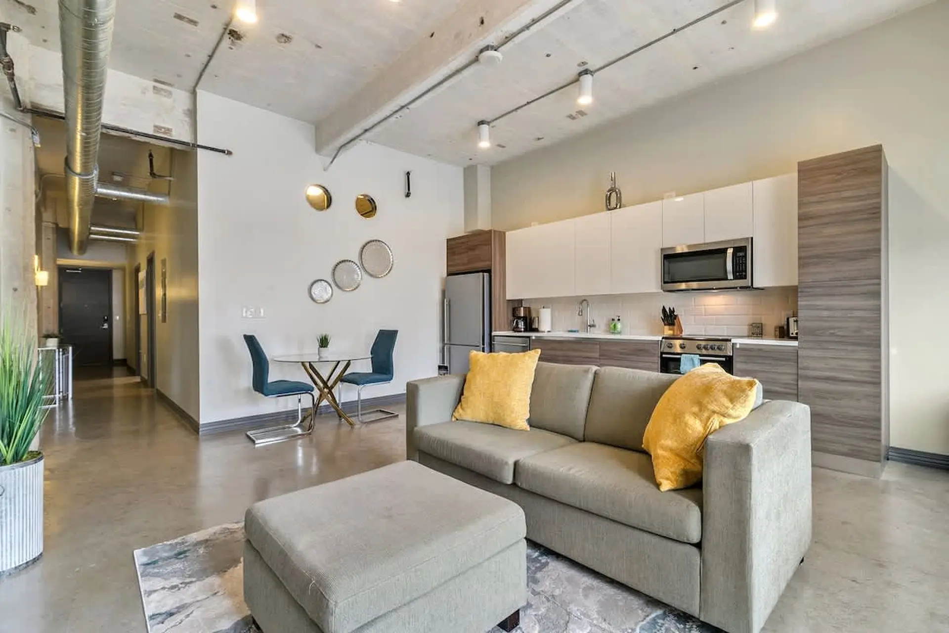Sofa and ottoman in a modern loft living room with an open-concept kitchen.