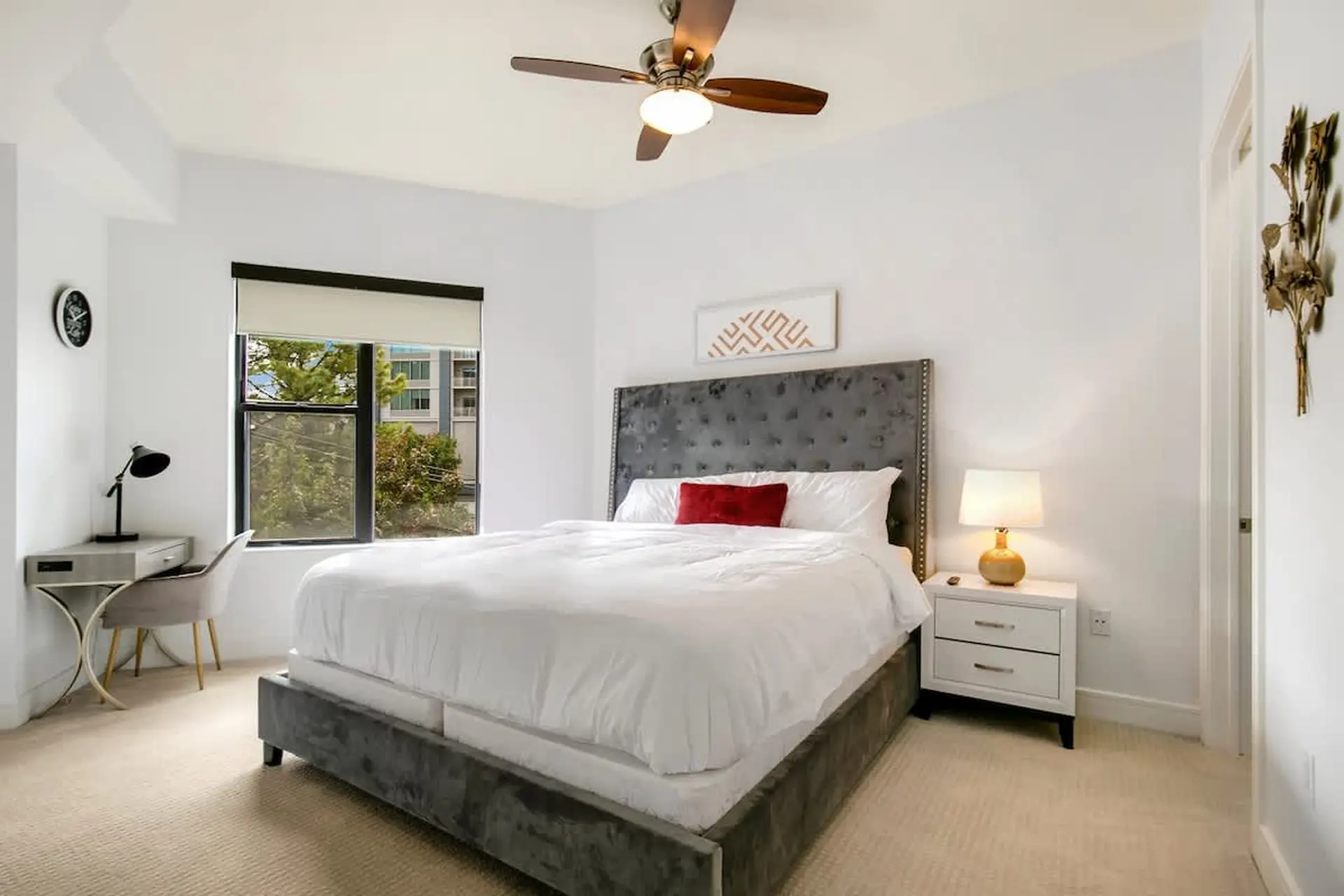 Bedroom with a large bed, a desk, a window, and a ceiling fan.