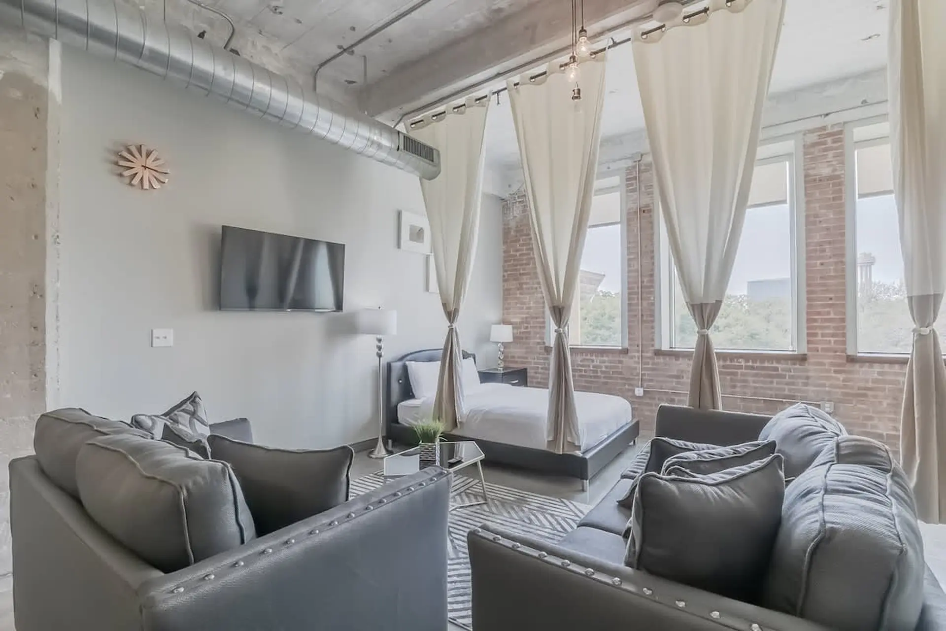 A loft apartment with a bed, sofas, and a TV in the living area.