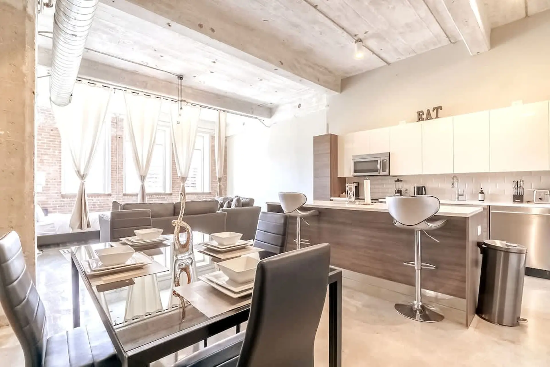 Modern loft apartment with dining table, sectional sofa, and kitchen island.