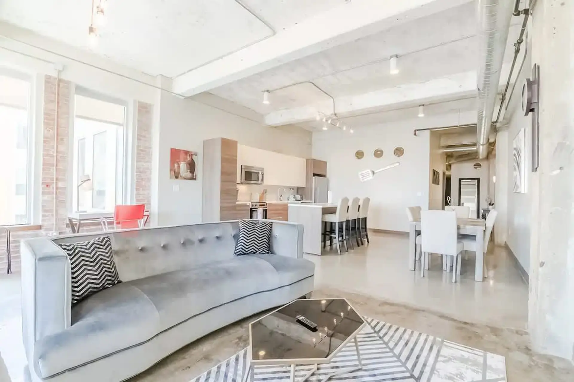 A modern loft apartment with a living area, kitchen, and dining room.