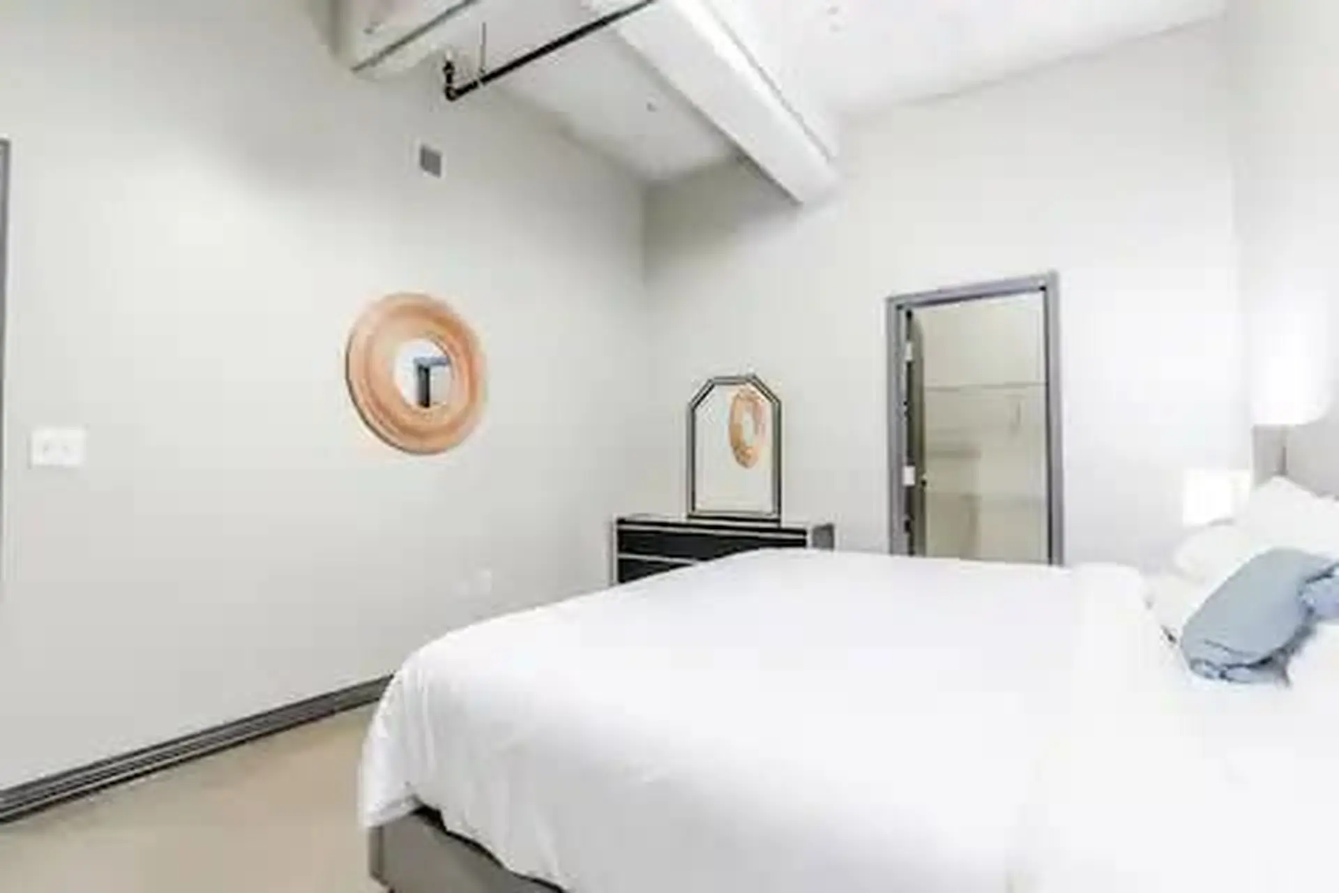 A bright bedroom with a bed, dresser, and mirror.