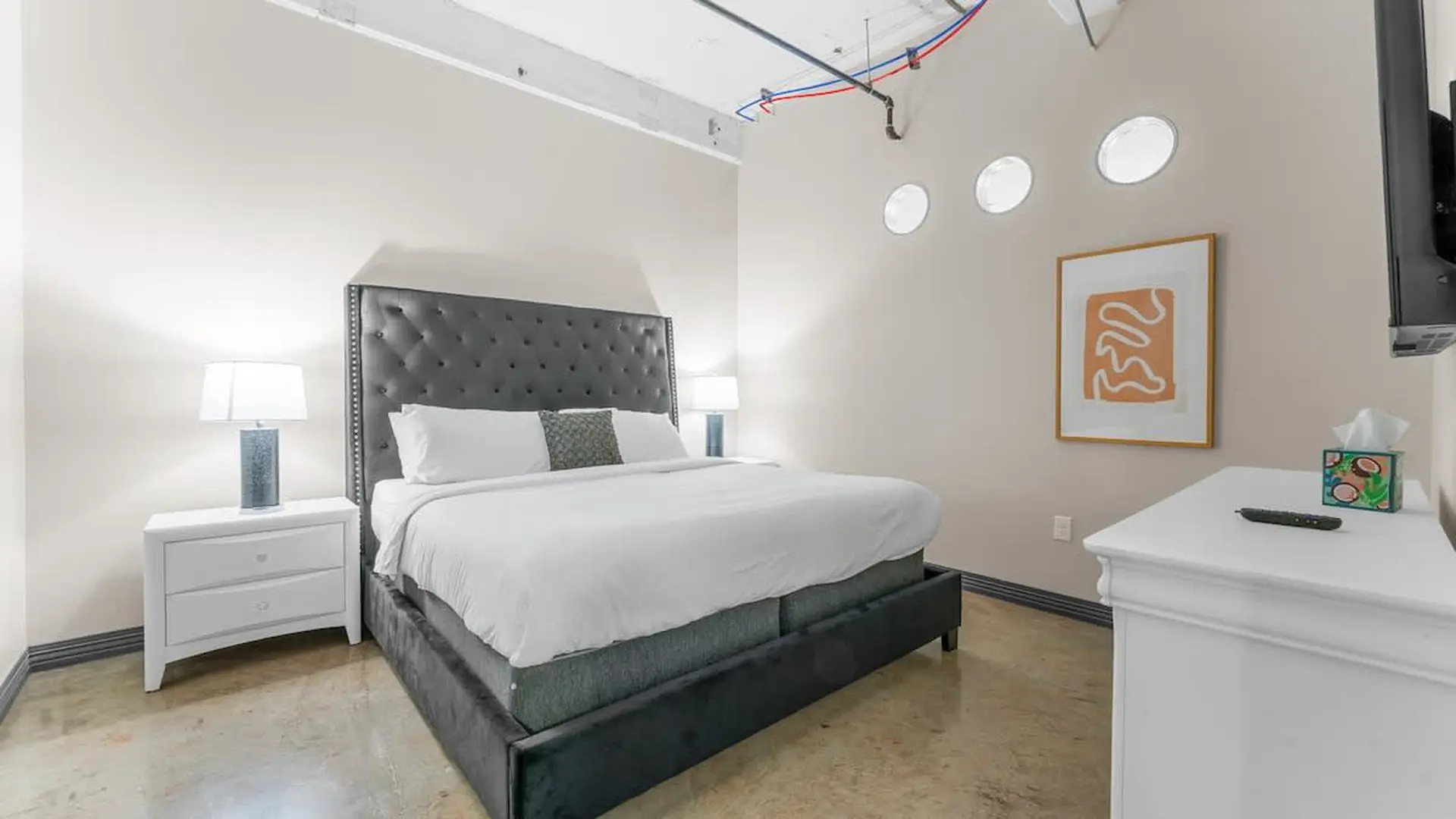 A plush headboard frames a king-size bed with white linens.