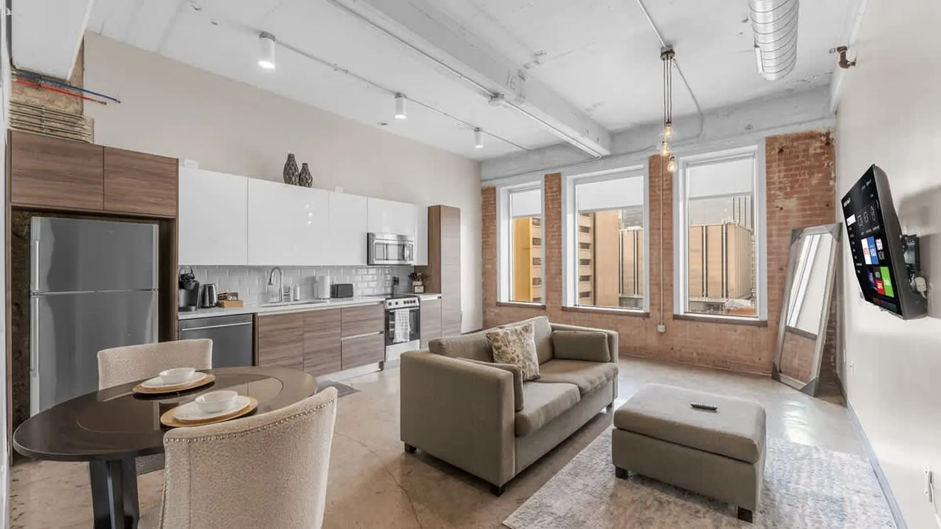 Modern loft apartment with kitchen, dining area, and living room with a sofa and TV.