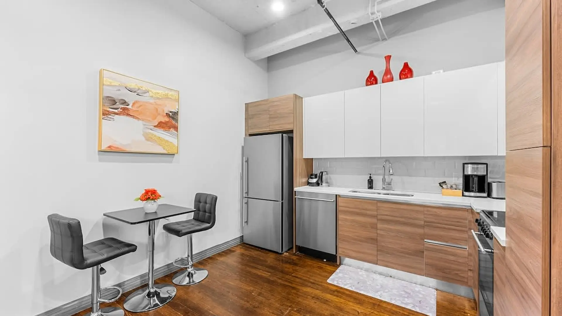 Modern kitchen with stainless steel appliances, wooden cabinets, and a small dining area.