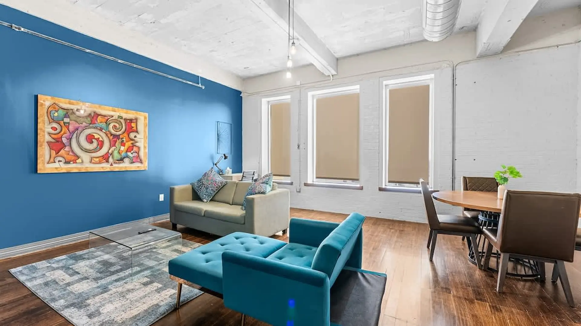 A blue sectional sofa and a taupe sofa in a loft with a glass coffee table.