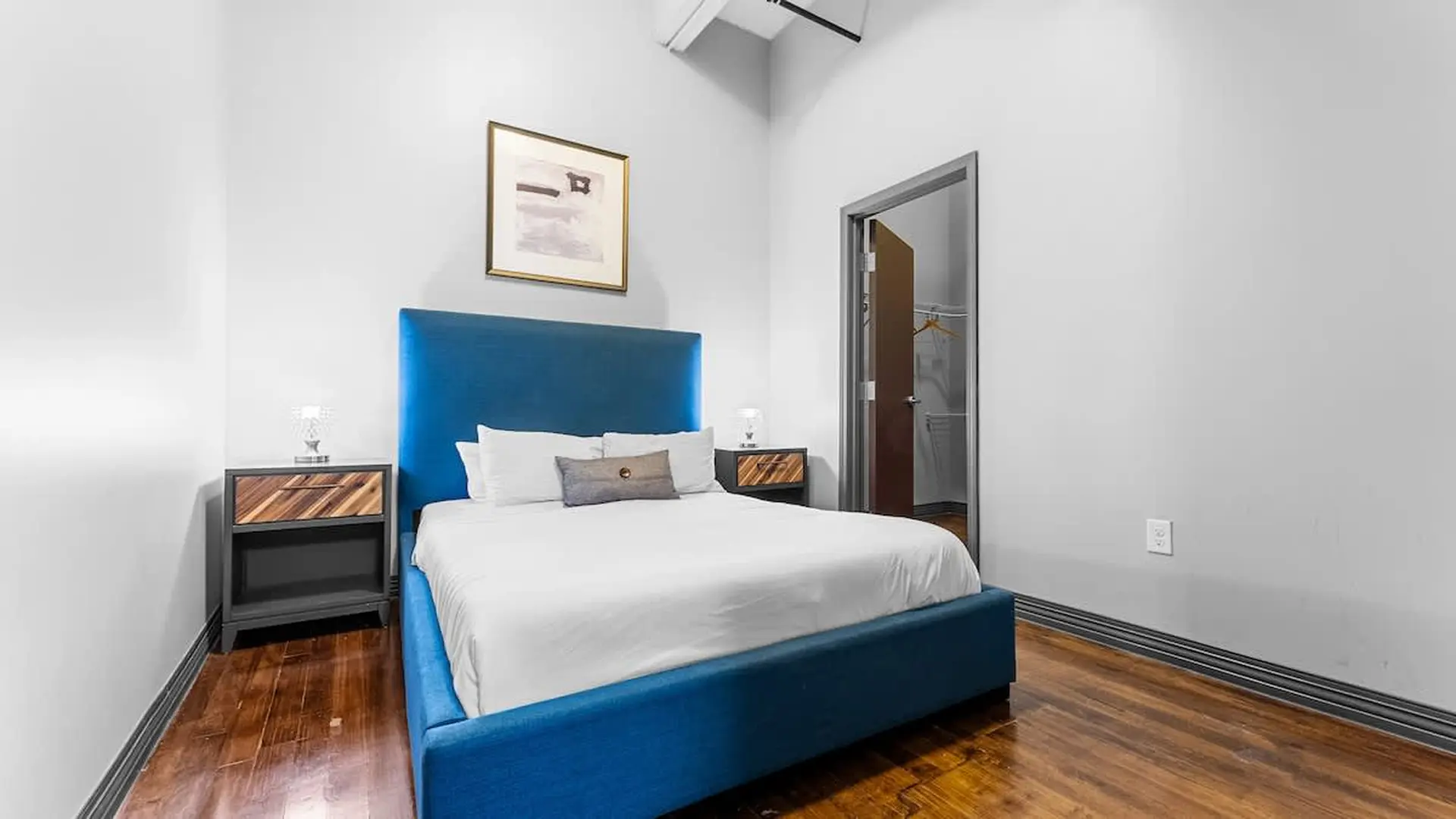 Bedroom with a blue headboard, white bedding, and a closet.