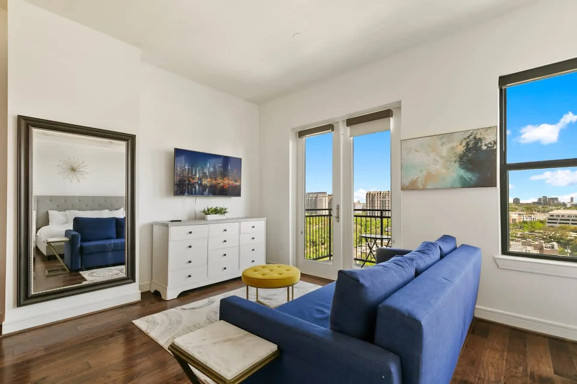 A living room with blue sofa, dresser, and a large mirror.