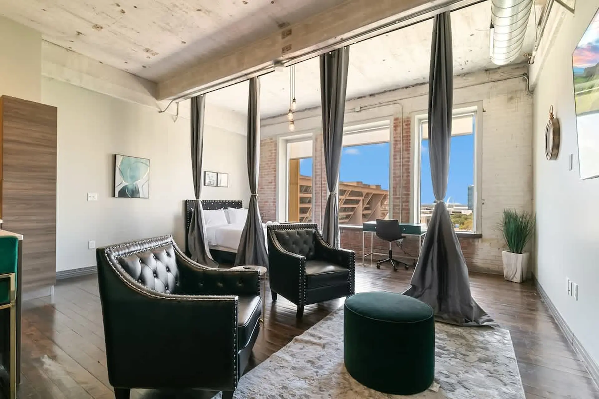 Stylish studio apartment with bed, seating area, desk, and city views.