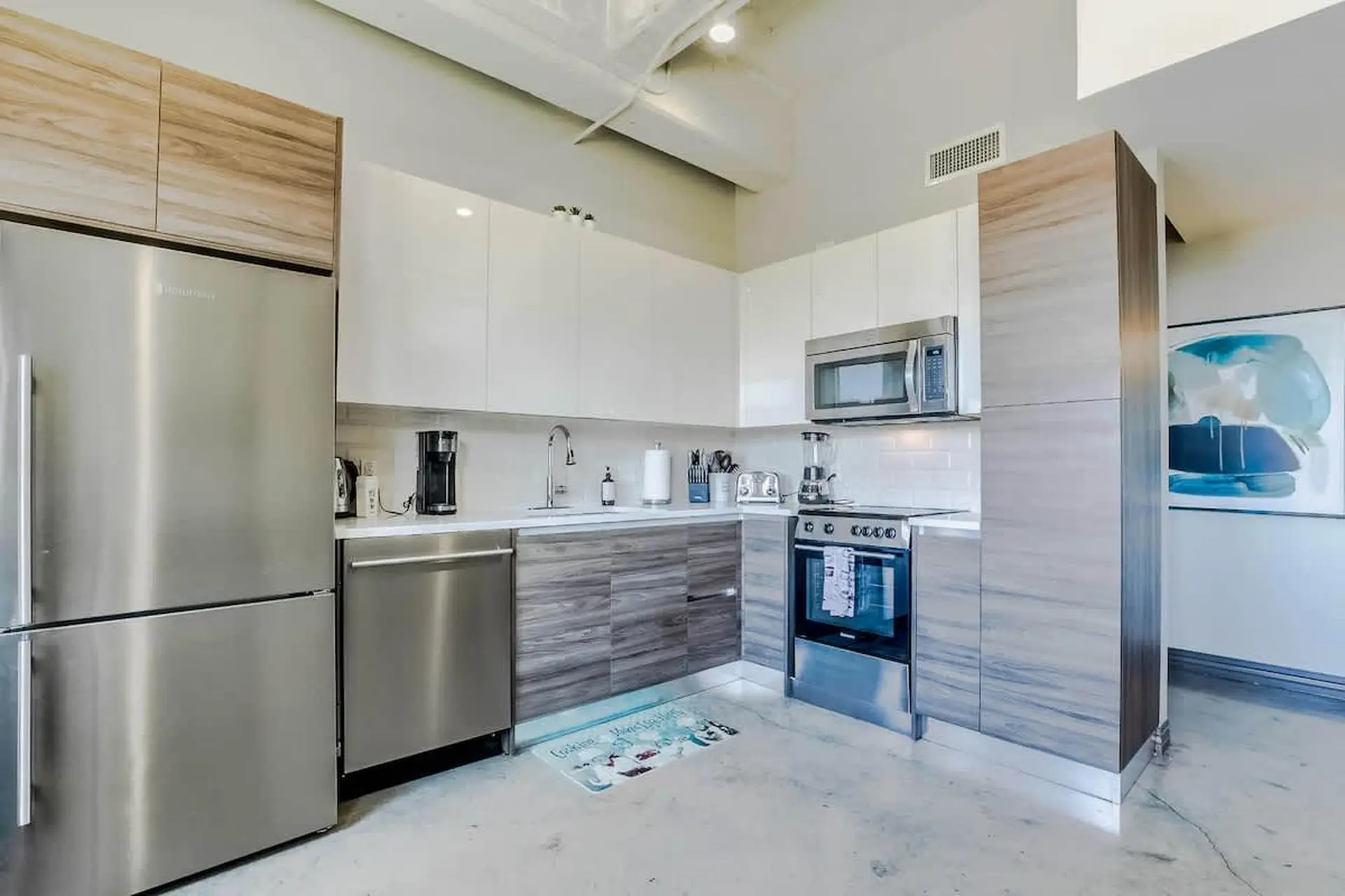 Modern kitchen with stainless steel appliances, white cabinets, and a wood-grain accent.
