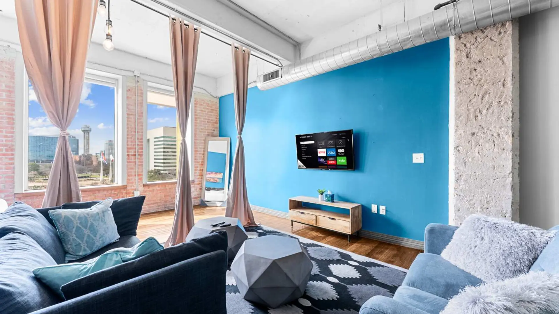 Living room with blue walls, couches, and geometric coffee tables.
