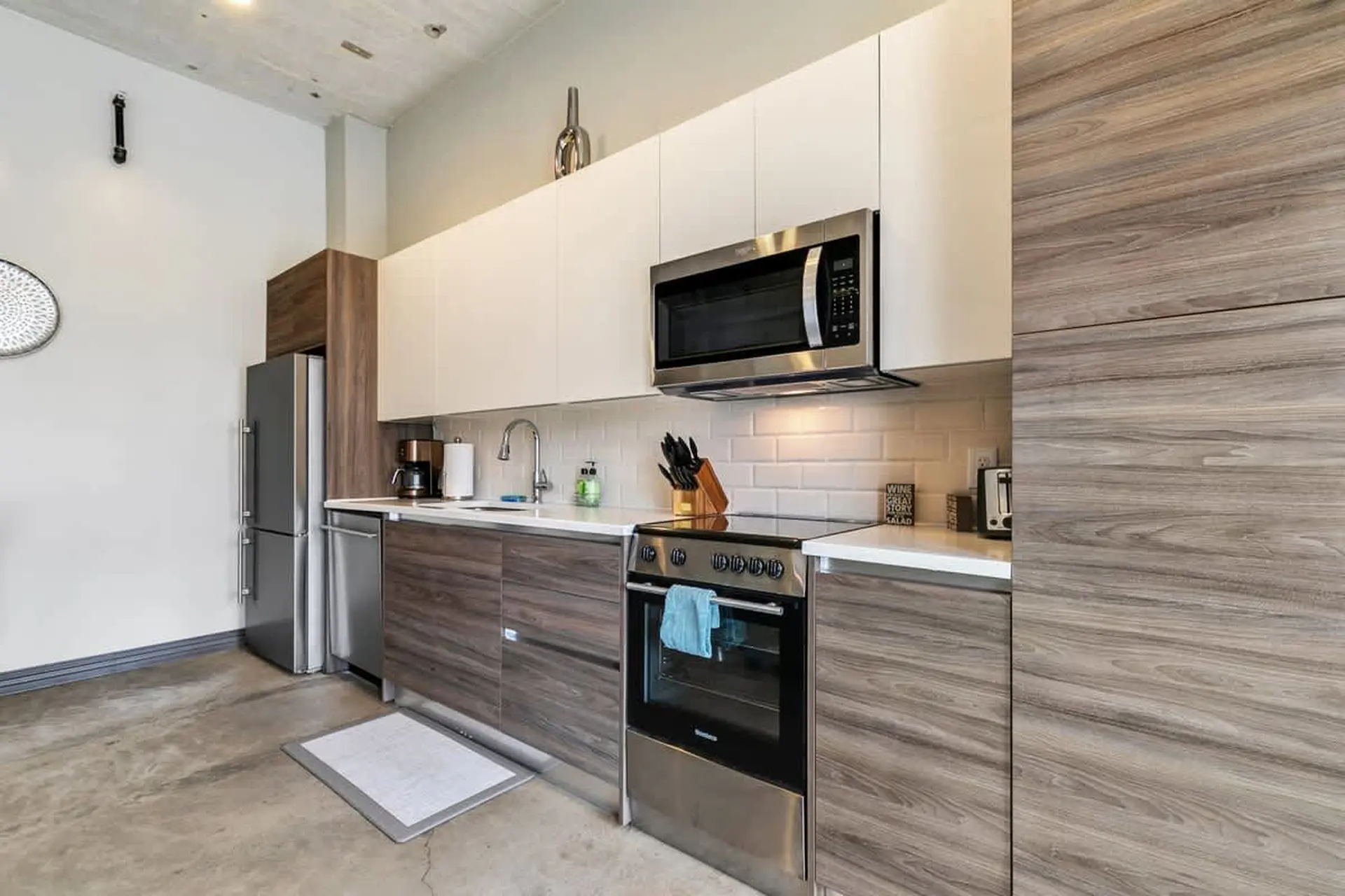 A modern kitchen with stainless steel appliances, wood cabinets, and white countertops.